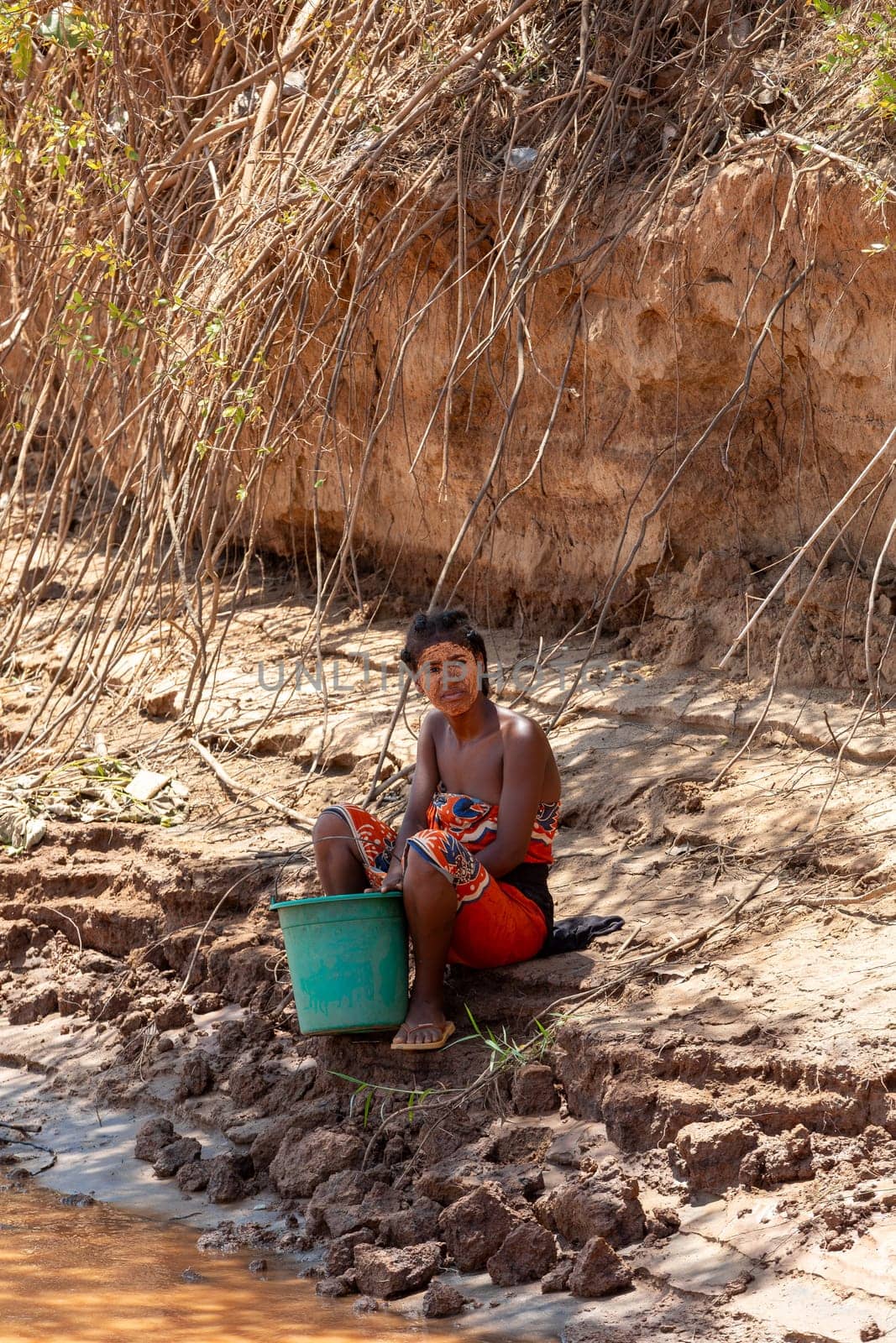 Belo Sur Tsiribihina, Madagascar - November 4th, 2022: An everyday moment of a woman collecting water by the river in Belo Sur Tsiribihina.