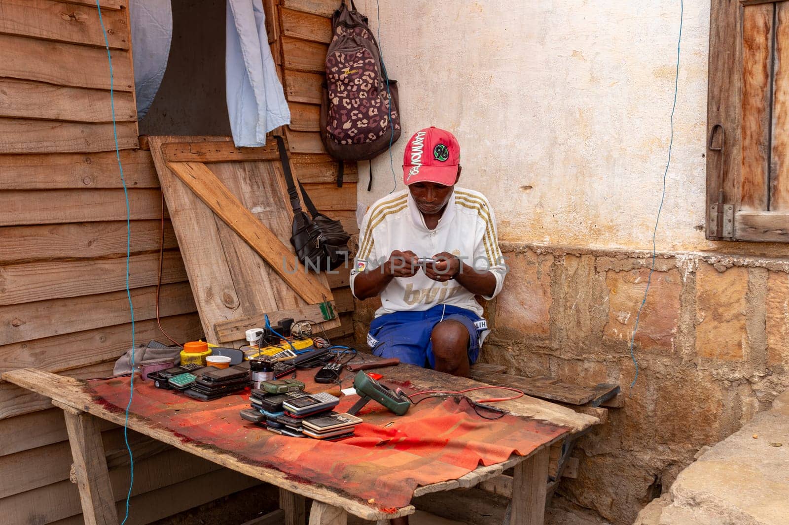 Miandrivazo, Madagascar - November 2nd 2022: Malagasy man works on repairing phones on the street of Miandrivazo, a town in Madagascar's Menabe region.