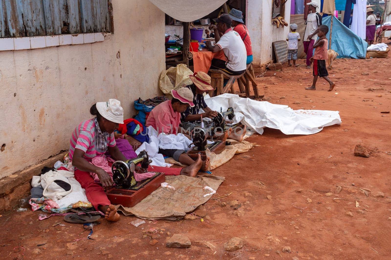 Mandoto, Madagascar - November 9. 2022: Street tailors, seamstress work with their outdated manual sewing machines. Earn some money in Madagascar is very difficult.