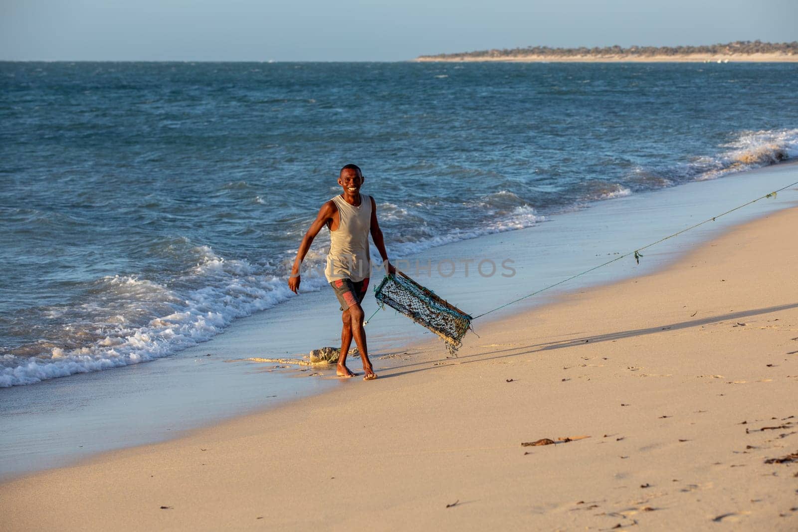 Anakao, Madagascar - November 21, 2022: A beach scene with a local fisherman and a cage for capturing crustaceans.