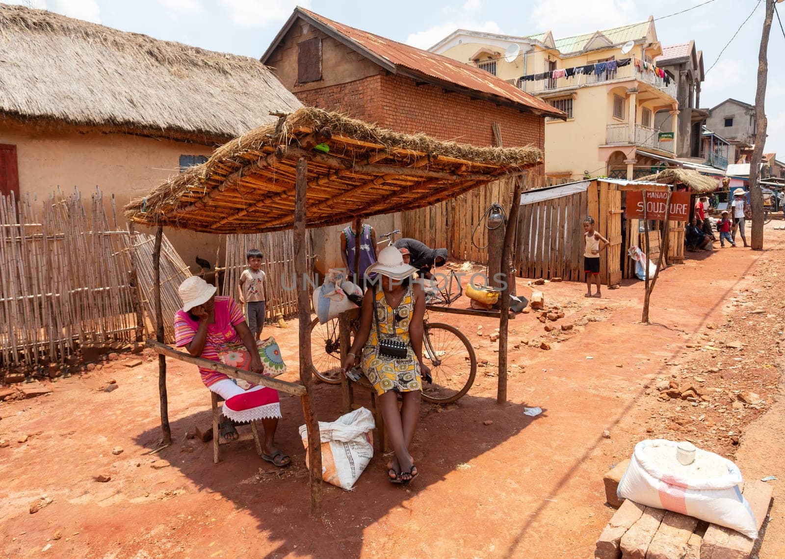 Mandoto, Madagascar - November 9th, 2022: Crowded street market in Mandoto city, with vendors and ordinary people shopping and socializing. Woman sell rice. Local lifestyle and economy of Madagascar.