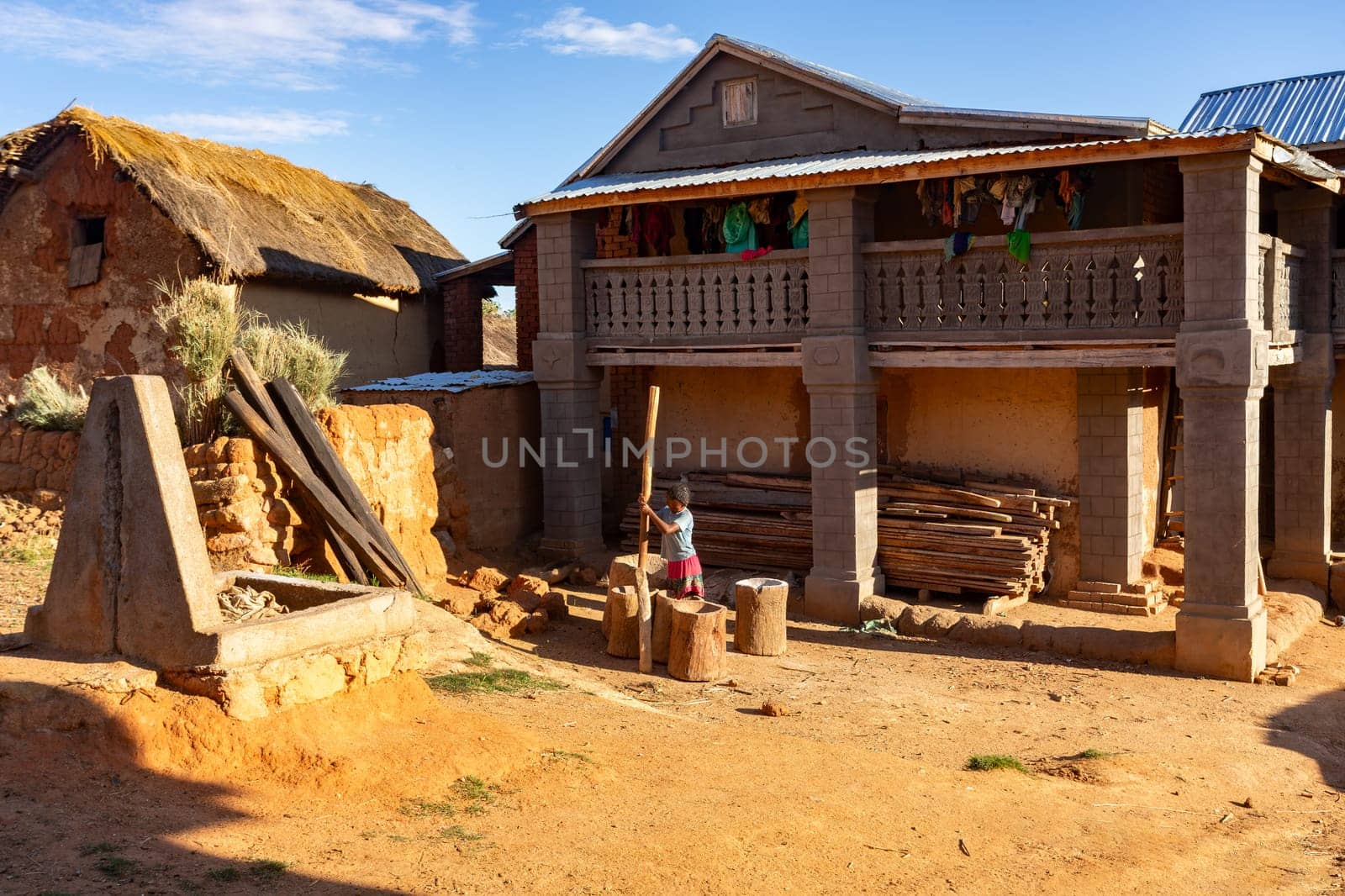 Andringitra Mountains, Madagascar - November 15, 2022: A young Malagasy woman living in the Andringitra Mountains prepares flour with primitive tools in a mortar.
