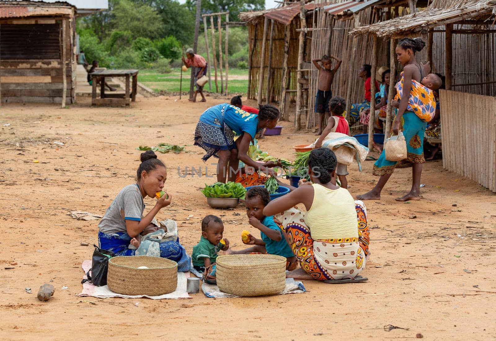 Bekopaka, Madagascar - November 6, 2022: Malagasy woman's with children selling vegetables on the street.