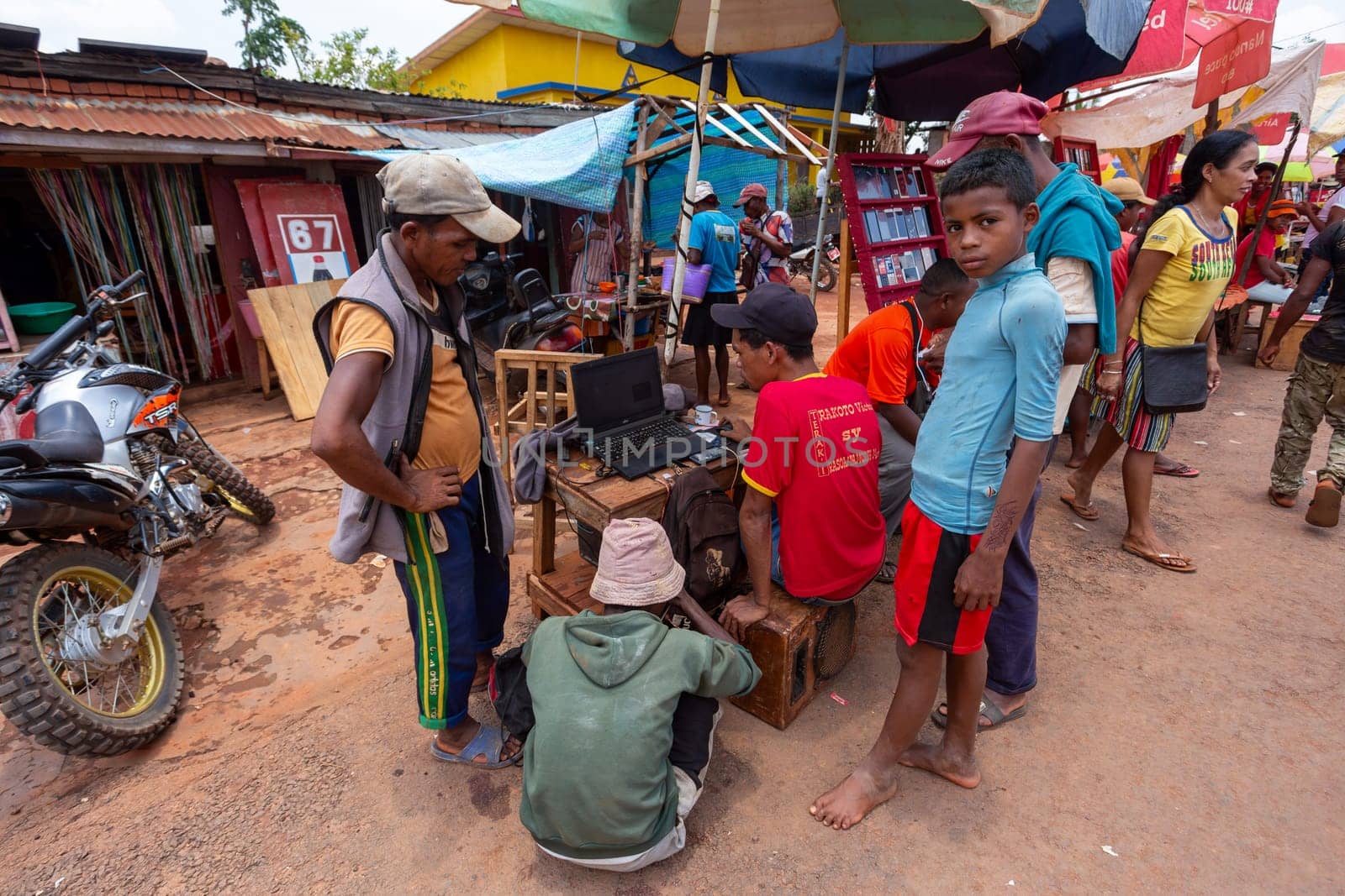 Mandoto, Madagascar - November 2nd 2022: A Malagasy man is seen working on repairing phone software using a laptop on the streets of Mandoto.