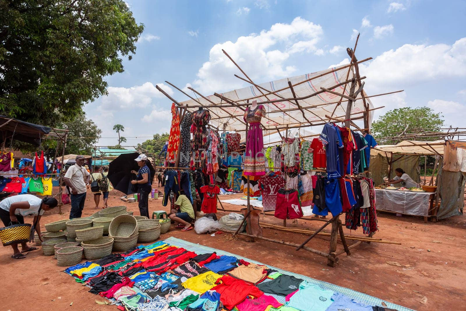 Mandoto, Madagascar - November 9th, 2022: A bustling street market in Mandoto city with vendors selling various types of clothes with vibrant colors.