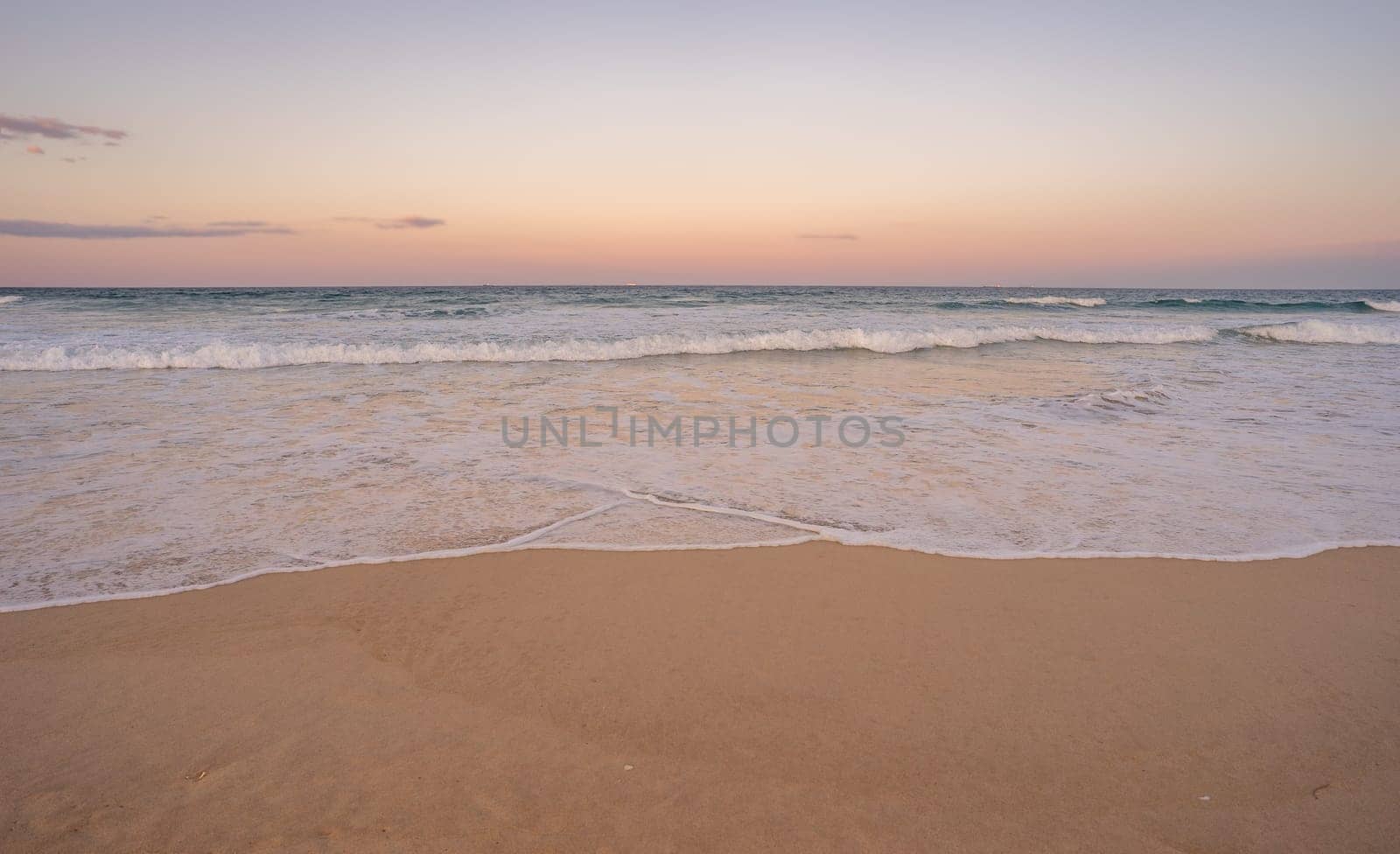 The surf and colorful sky at dusk along Kawana beach on the Sunshine Coast, Queensland, just before the Blue Moon rises above the horizon along the east coast of Australia 2023