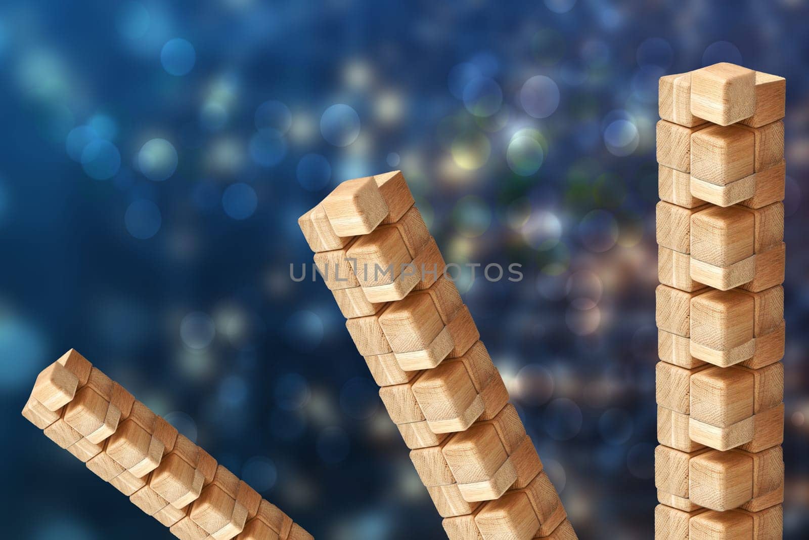 Towers from wooden blocks over abstract blurred blue technology or business  background with bright rays. Copy space. Wood blocks game.