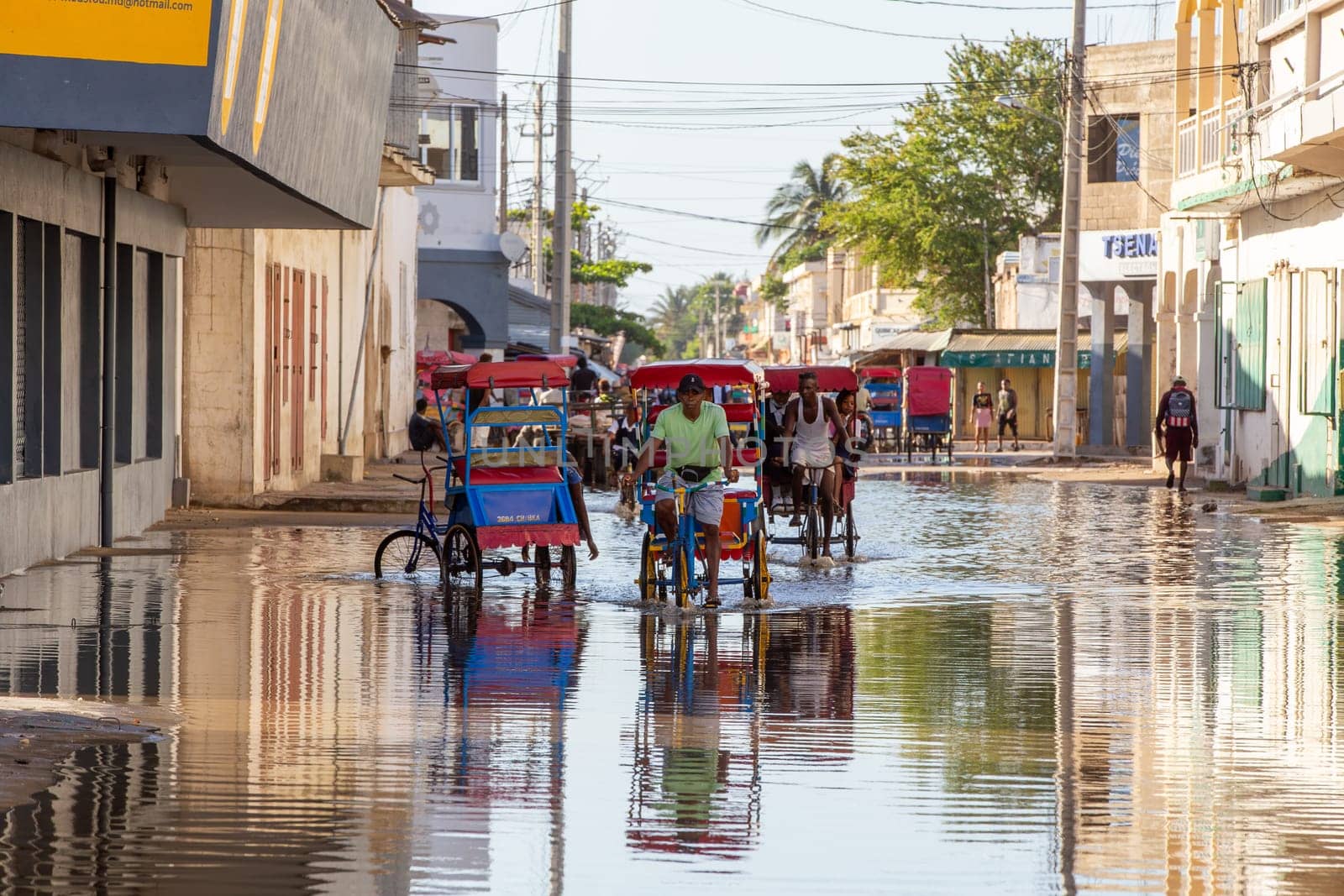 Toliara, Madagascar - November 21. 2022: Traditional rickshaw bicycle with Malagasy passengers on the street, one of the ways to earn money. Everyday life on the cities street of Madagascar.