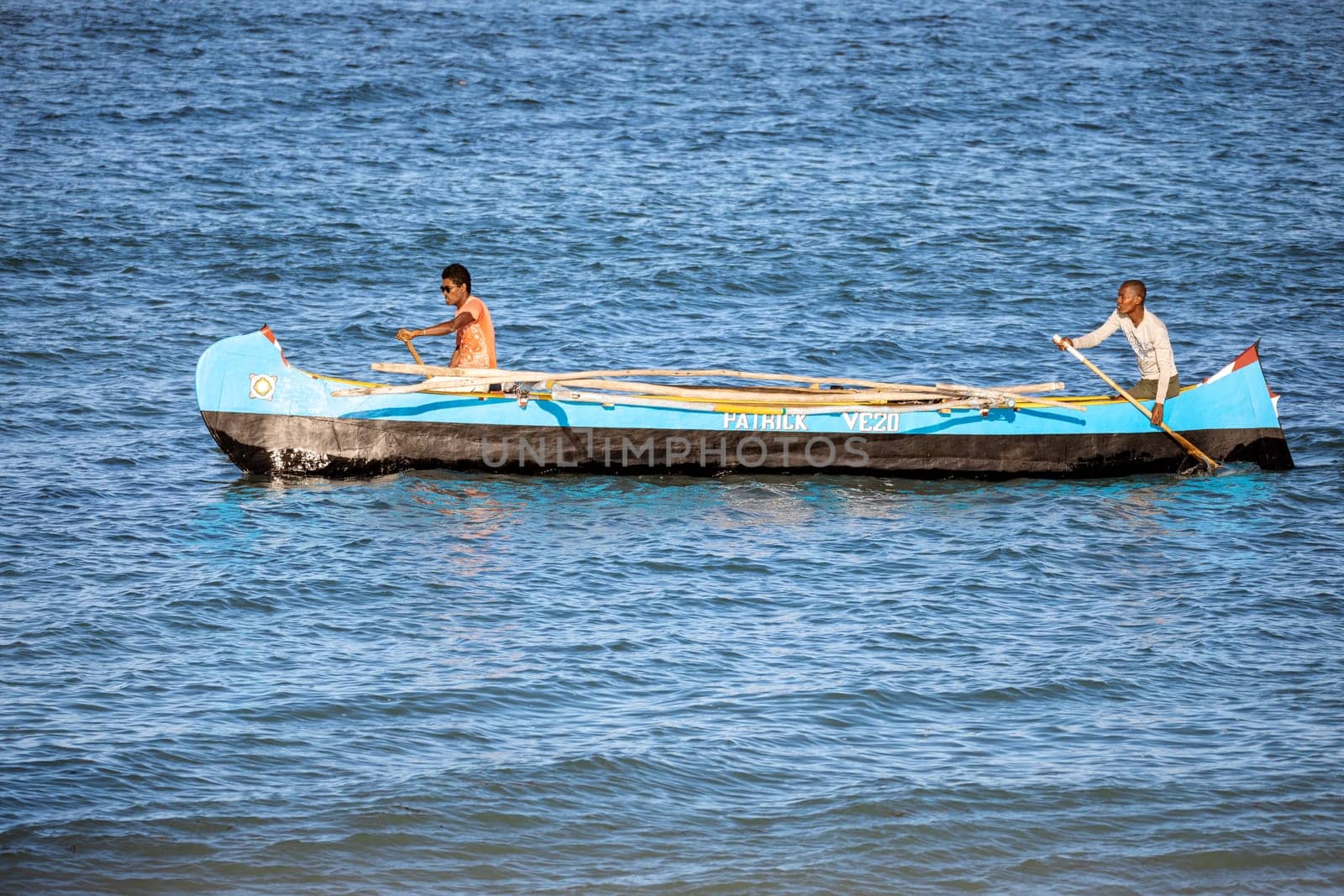ANAKAO, MADAGASCAR - NOVEMBER 22, 2022: Fishermen using outrigger canoe carved from tree trunk to fish off the coast of Anakao. The primary source of livelihood in Anakao is fishing.
