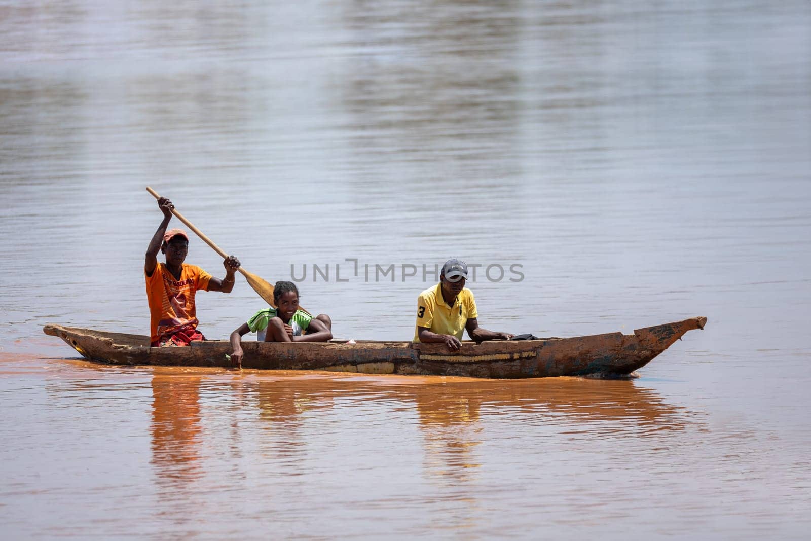 Port Bac Belo Sur Tsiribihina, Madagascar - November 4th, 2022: Malagasy family in traditional wooden boat ride on the Mania River in Madagascar.
