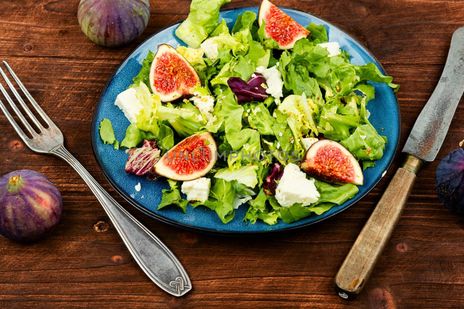 Appetizer homemade salad with figs, herbs and cheese.