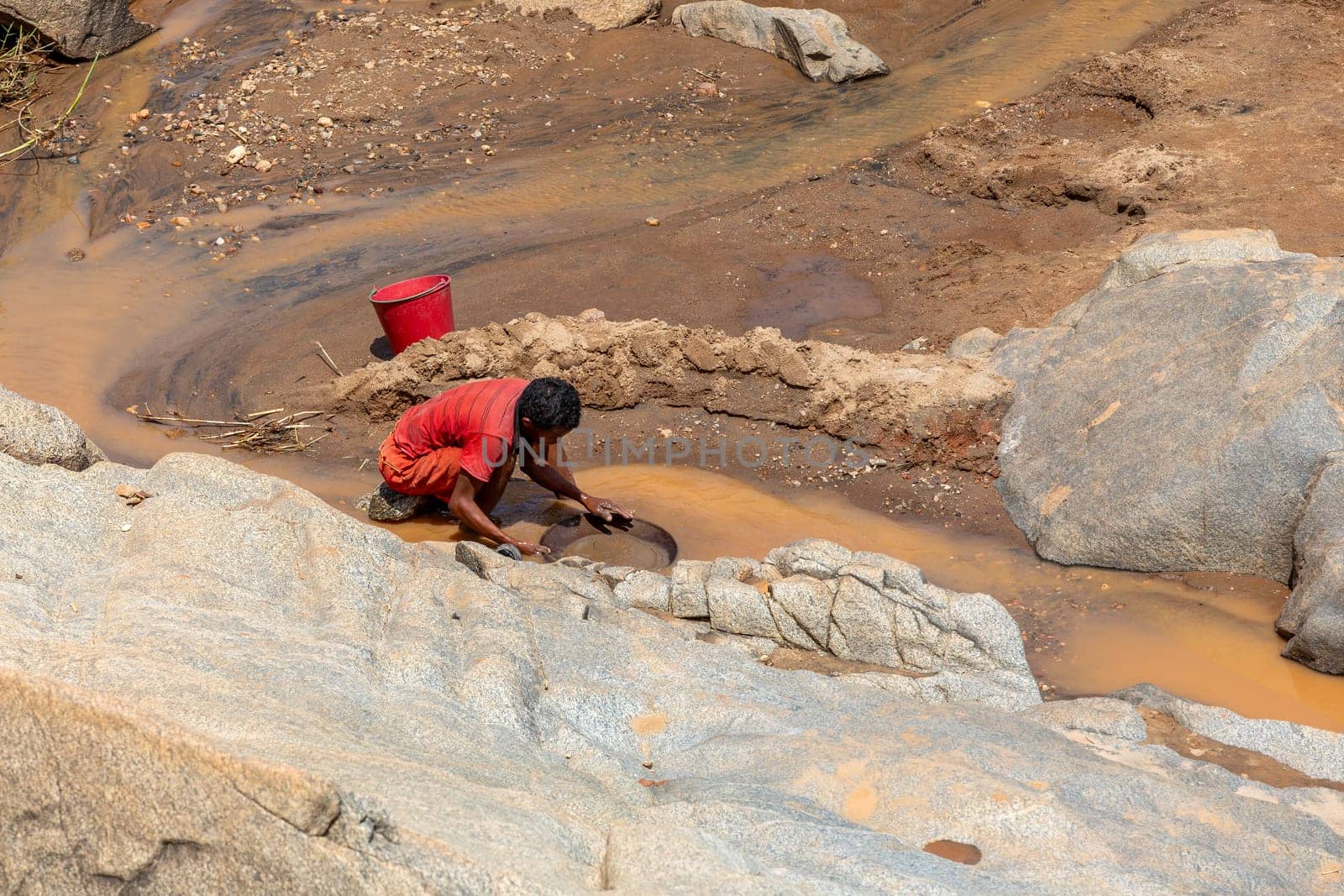 Dabalava, Madagascar - November 1, 2022: Local people mine for gems and pan for gold in a river. If they're lucky, they'll find a little gold flake