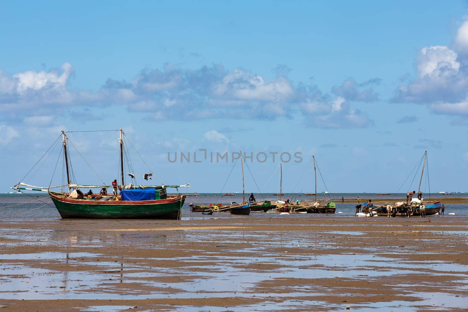 Toliara, Madagascar - November 21st 2022: Fishing boat stranded on the dry port during low tide with Malagasy people around.