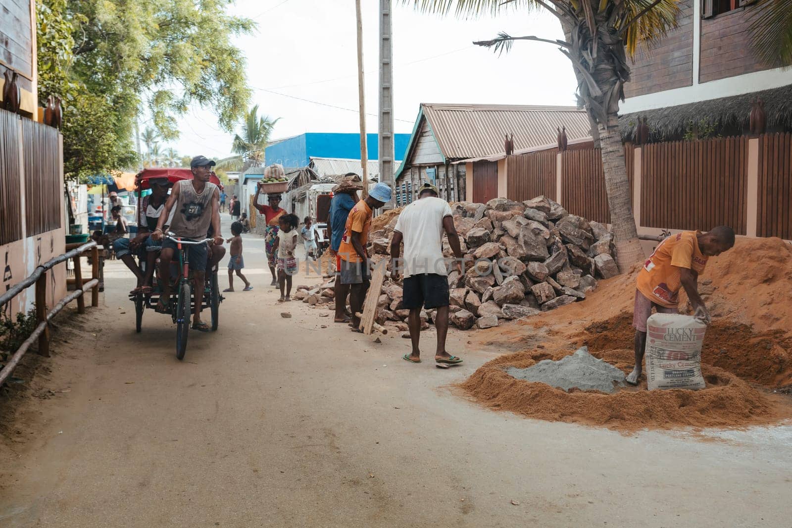 Morondava, Madagascar - November 3rd, 2022: Malagasy men working hard, manually carrying construction stones.
