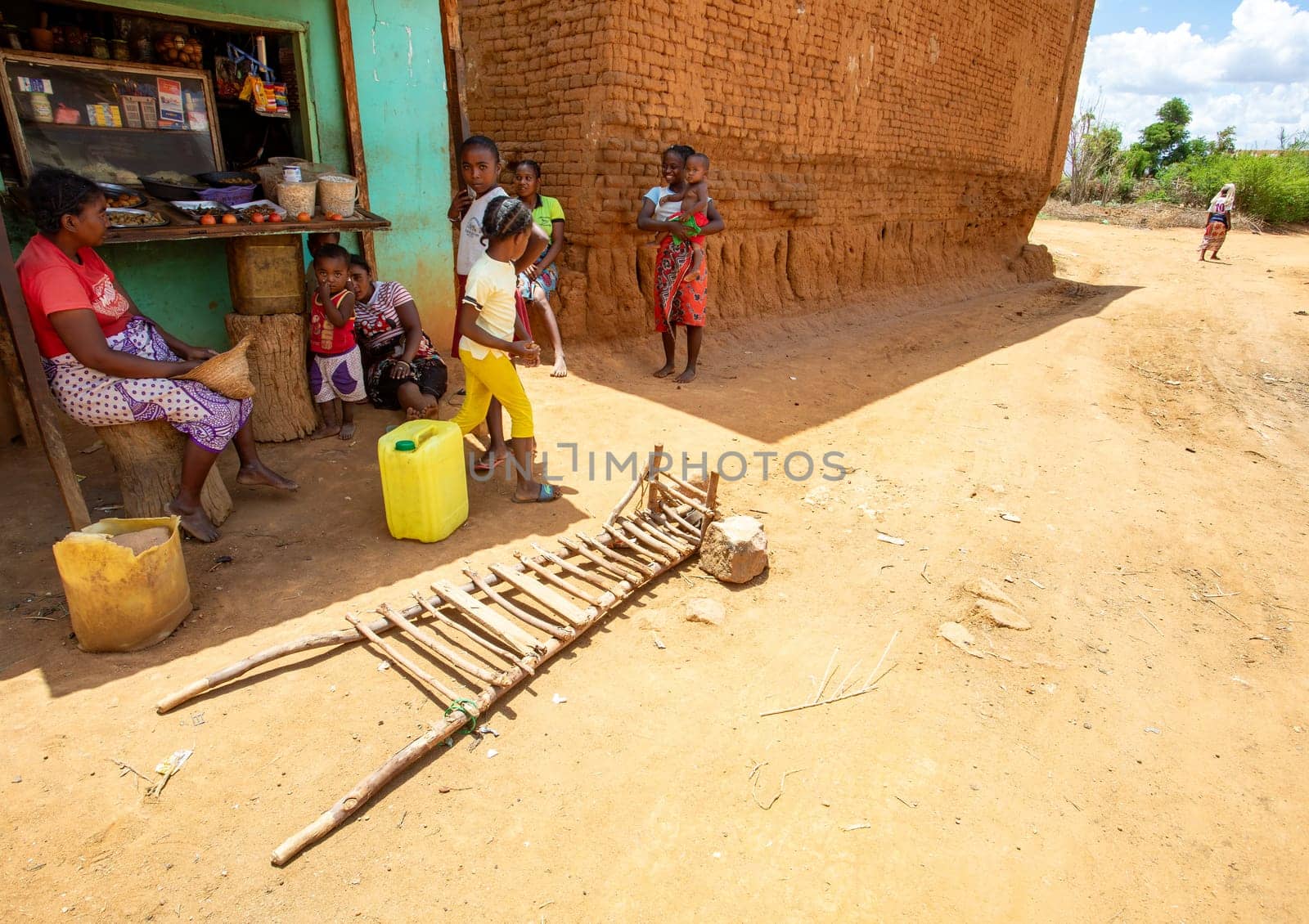 Vohitsoaka Ambalavao - November 6, 2022: Malagasy woman resting in front of market in shadow. In the foreground is a primitive wheelbarrow
