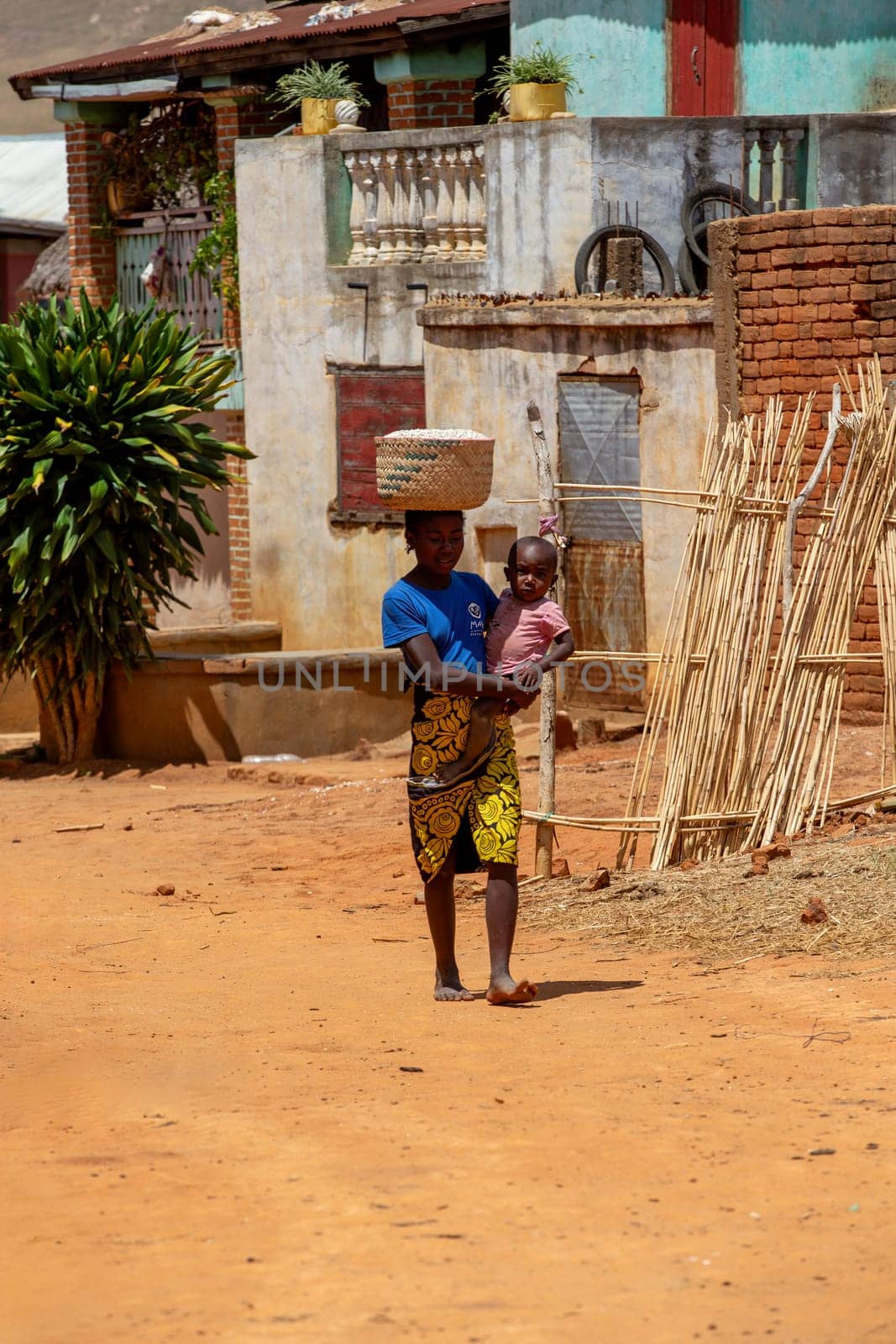 Vohitsoaka Ambalavao - November 6, 2022: Malagasy woman walking down the street with a child on her back.