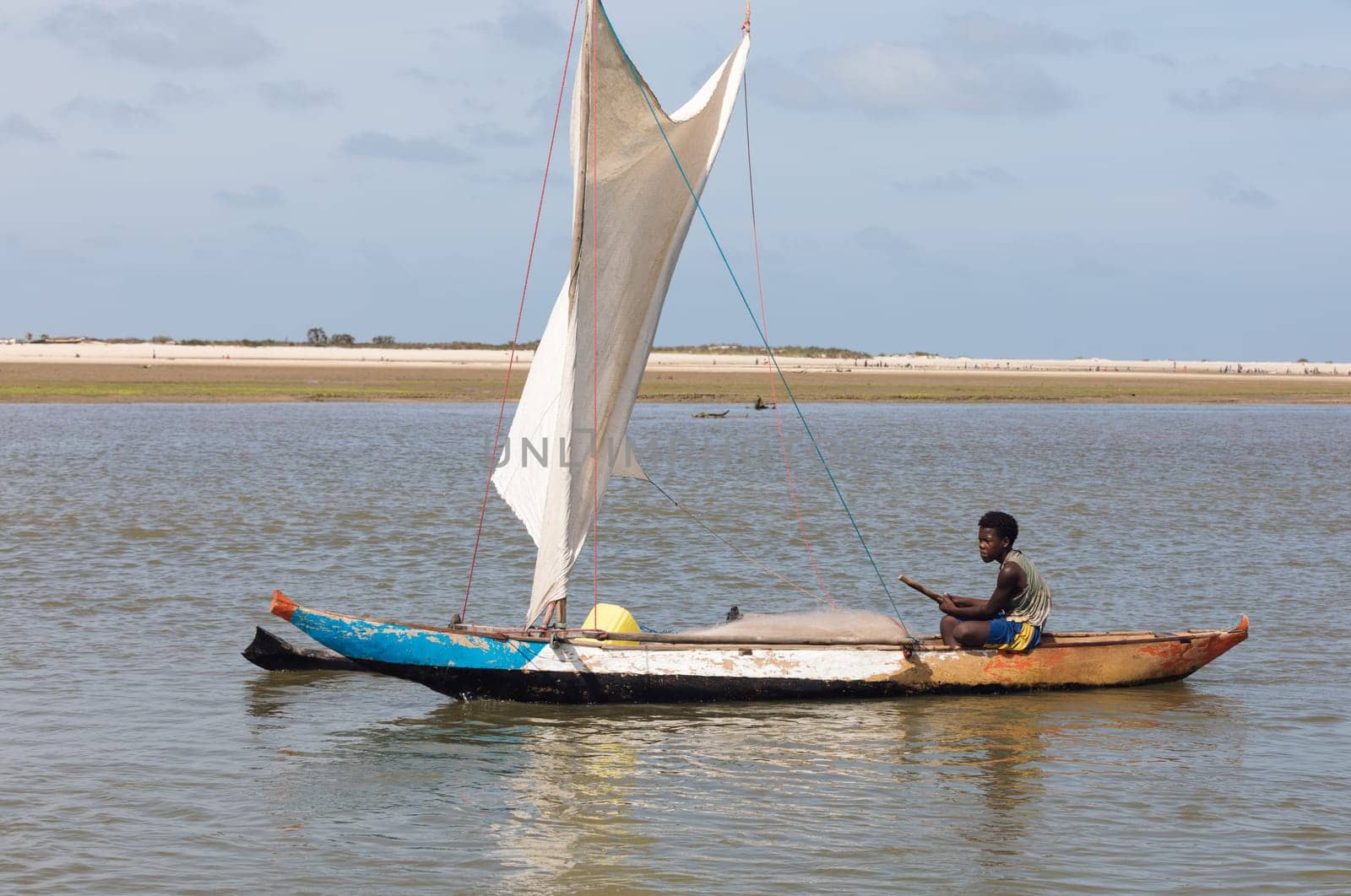 Morondava, Madagascar - November 3rd 2022: A fisherman sails back from the sea to the river on a sailboat in Morondava