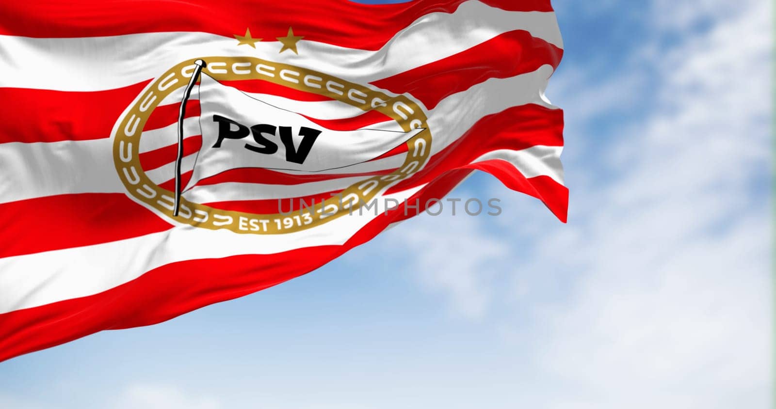 Eindhoven, NL, Sept. 4 2023: PSV Eindhoven football club waving in the wind on a clear day. Dutch sports club from Eindhoven. Illustrative editorial 3d illustration render. Fluttering fabric