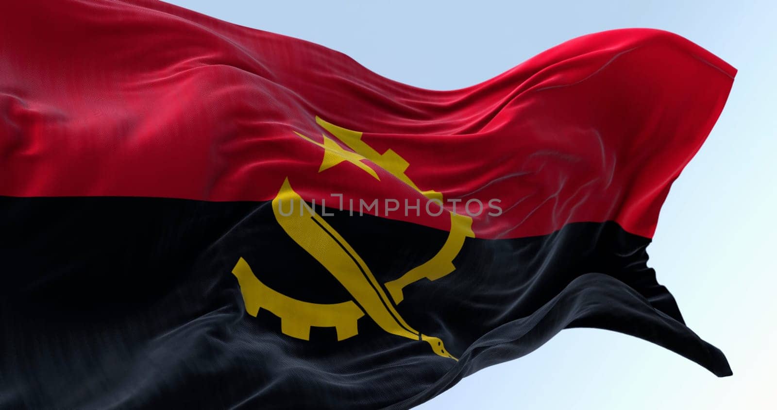The national flag of Angola waving in the wind on a clear day. Two horizontal bands, red and black, with a yellow emblem in the center. 3d illustration render. Fluttering fabric
