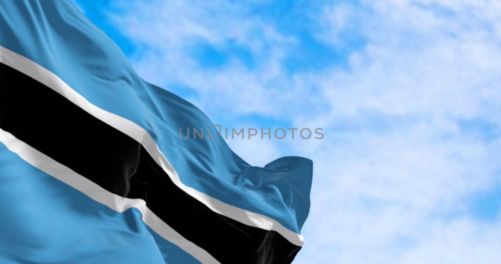 National flag of Botswana waving in the wind on a clear day. Light blue field with a horizontal black and white stripe in the center. 3d illustration render. Fluttering fabric