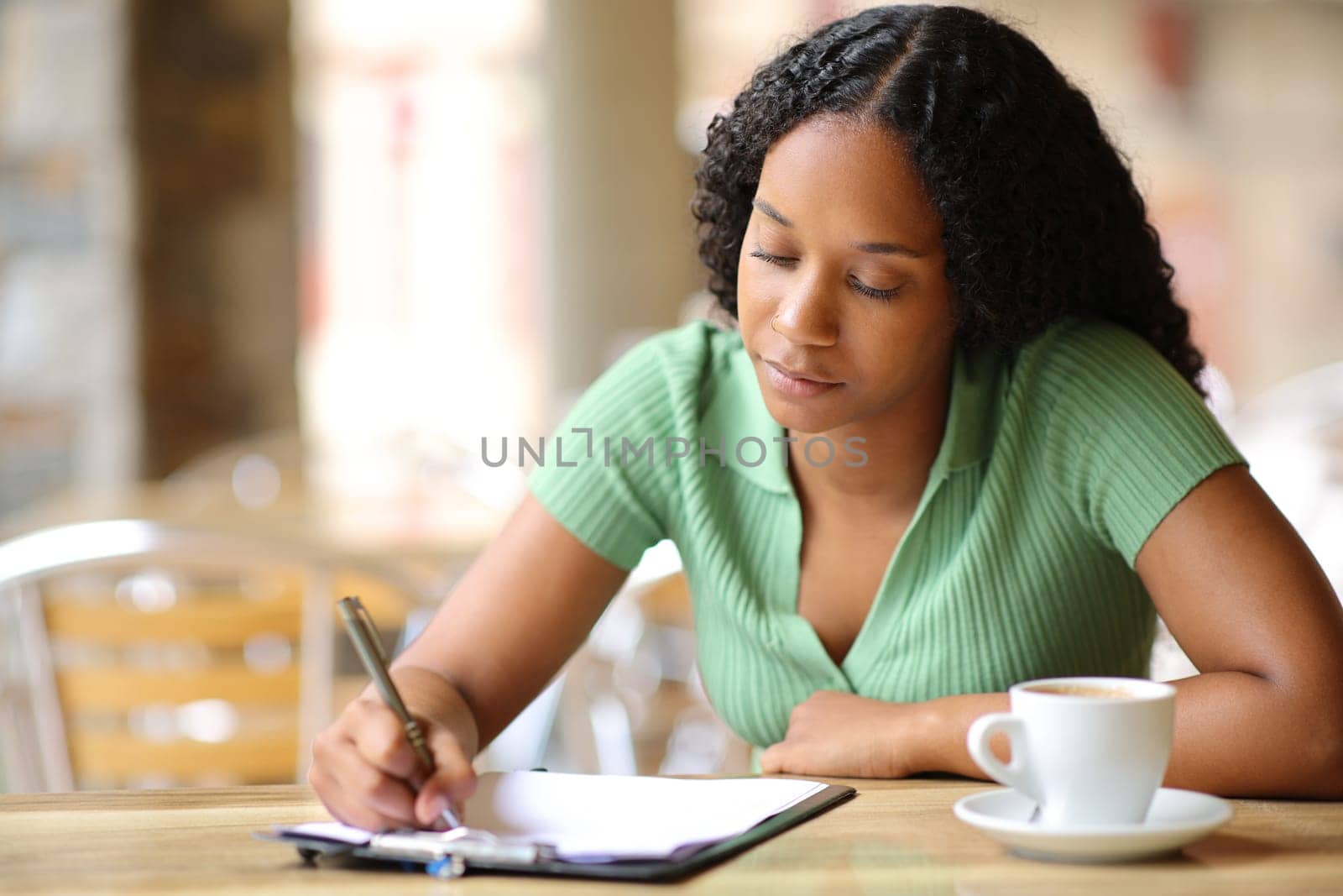 Black woman filling form or survey sitting in a bar terrace
