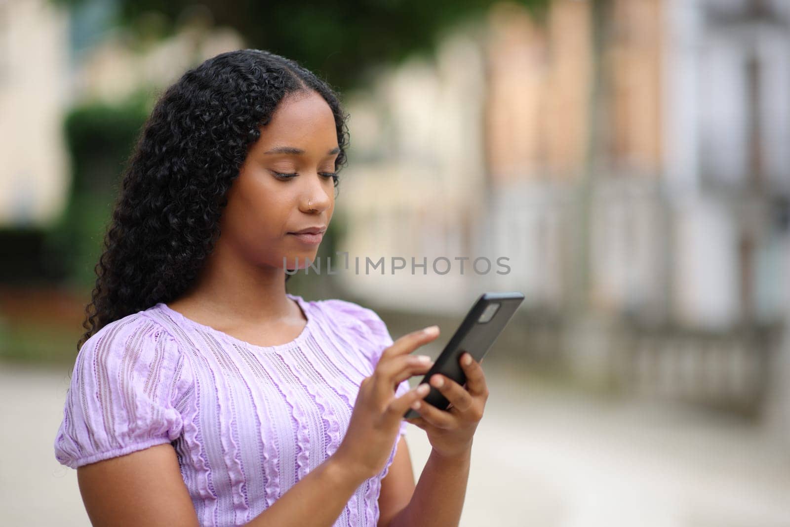 Black woman using cell phone walking in the street