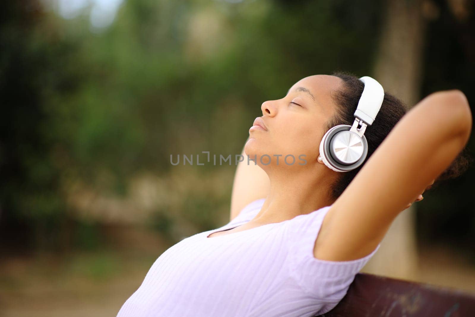 Side view portrait of a black woman resting listening audio with heaphone