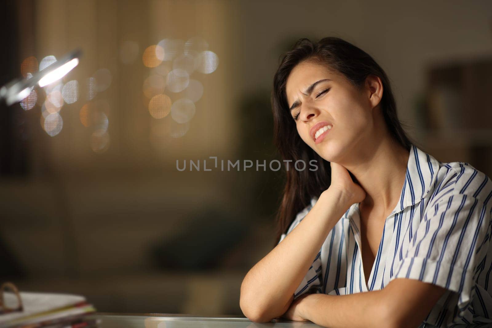 Stressed woman suffering neck ache and complaining sitting in the night at home