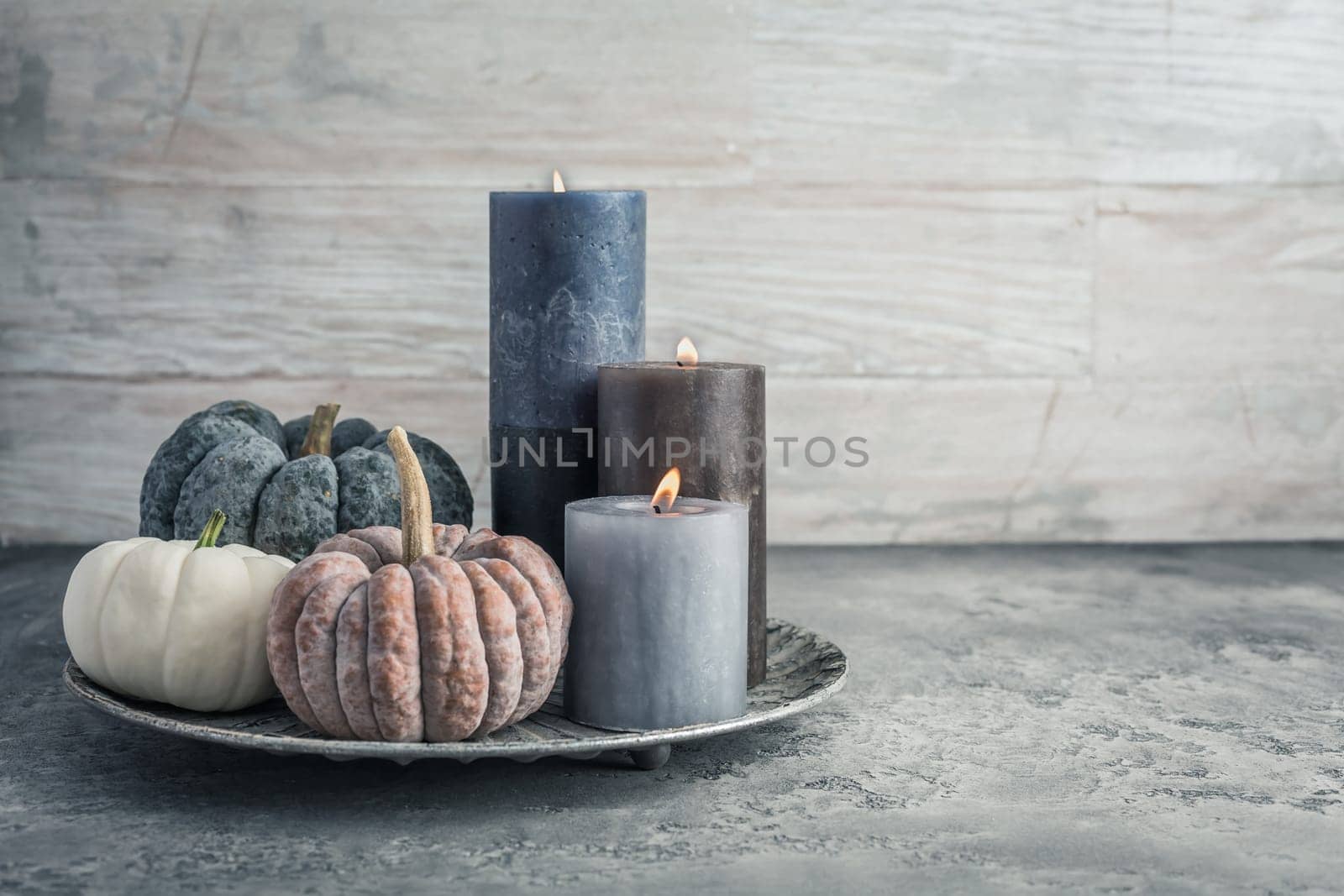 Autumn fall cozy mood composition for hygge home decor.  Candles and pumpkins for Thanksgiving in grey tone