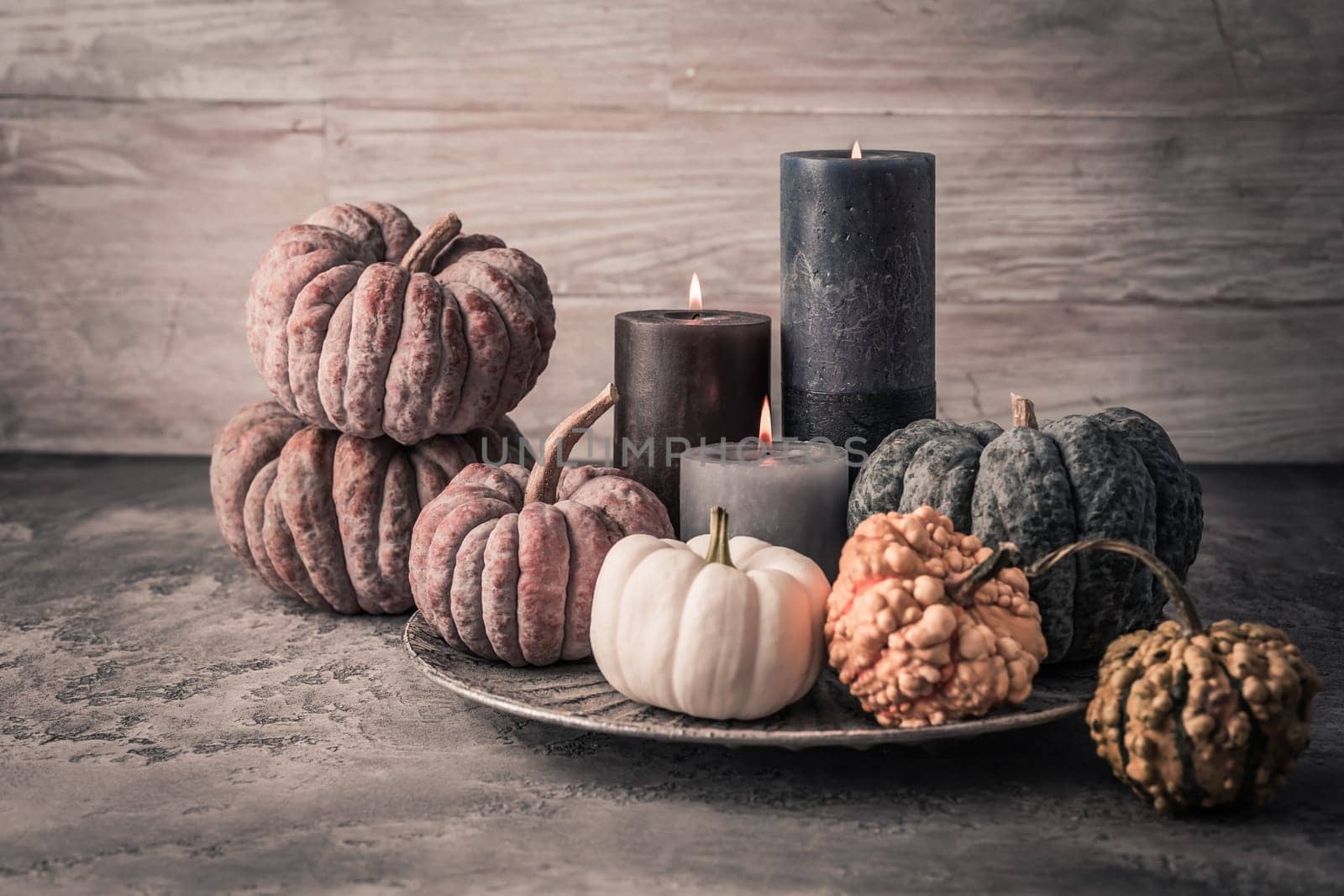 Autumn fall cozy mood composition for hygge home decor.  Candles and pumpkins for Thanksgiving in grey tone