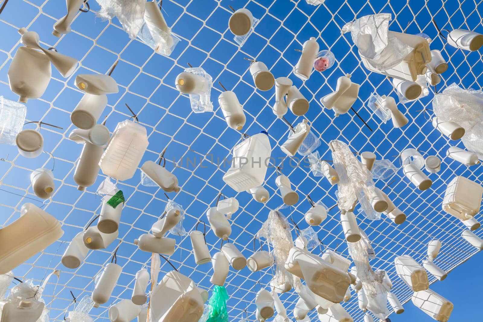 Plastic containers in fishing net against blue sky -  concept of garbage, water pollution, environmental issue