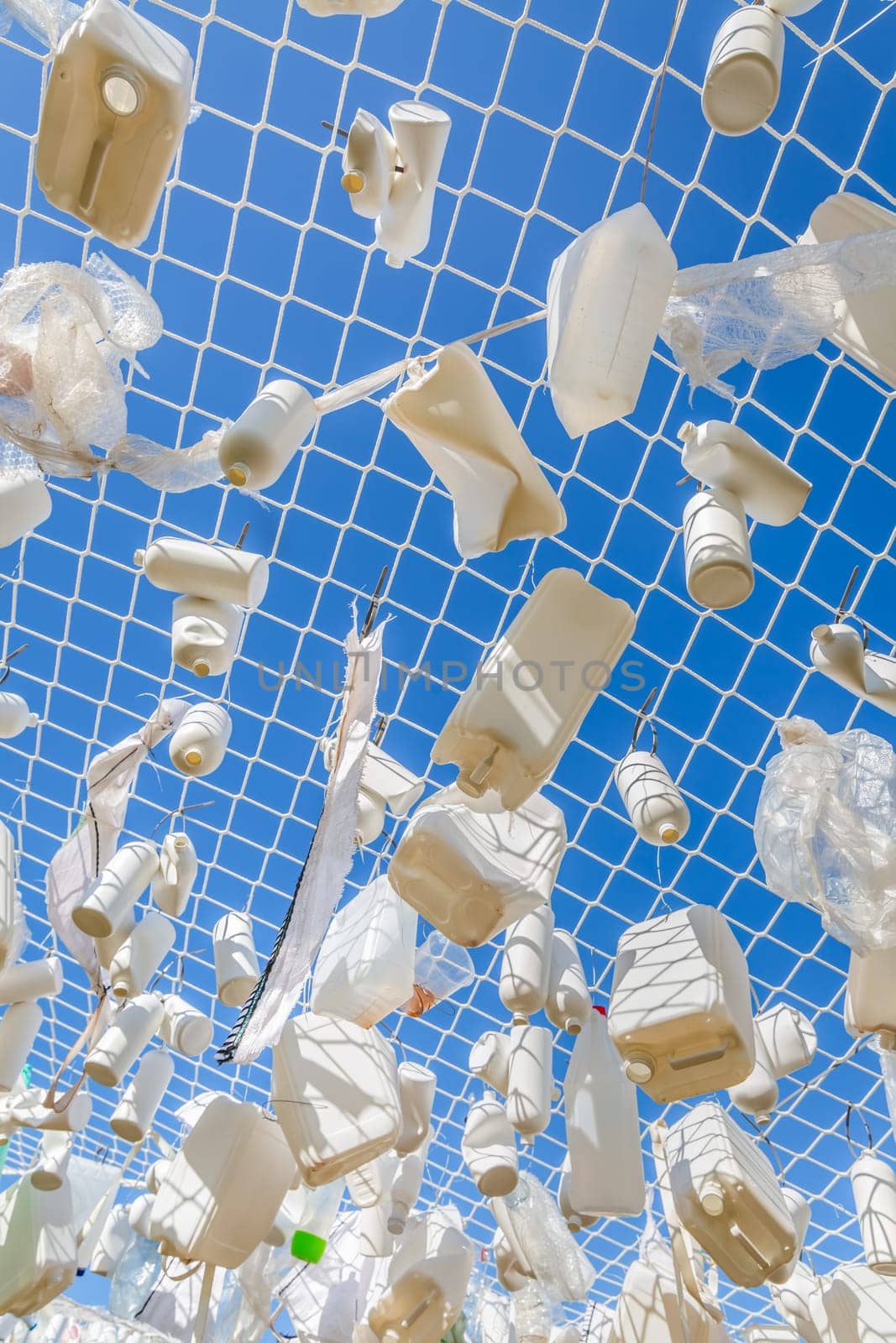 Plastic containers in fishing net against blue sky -  concept of garbage, water pollution, environmental issue