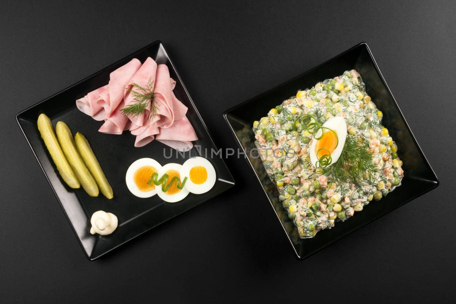 Luxury gourmet appetizer with Russian salad, ham, eggs and pickle on black background.
