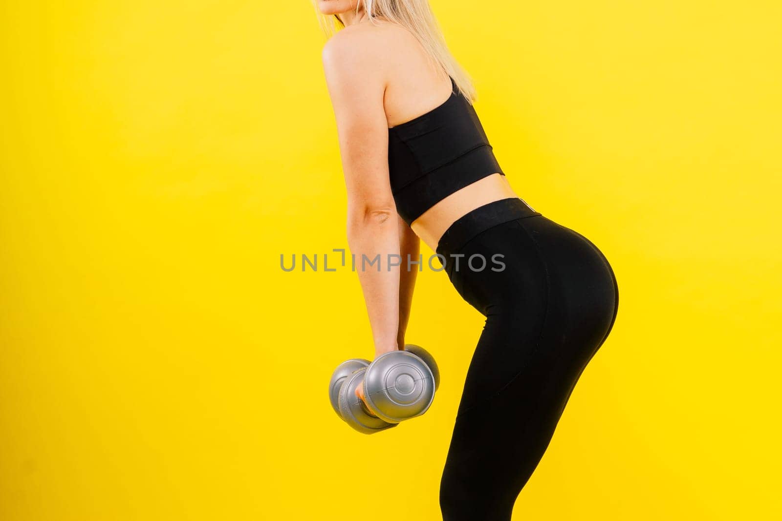 Perfect sporty female working out with dumbbells. Photo of woman in sportswear, studio shot
