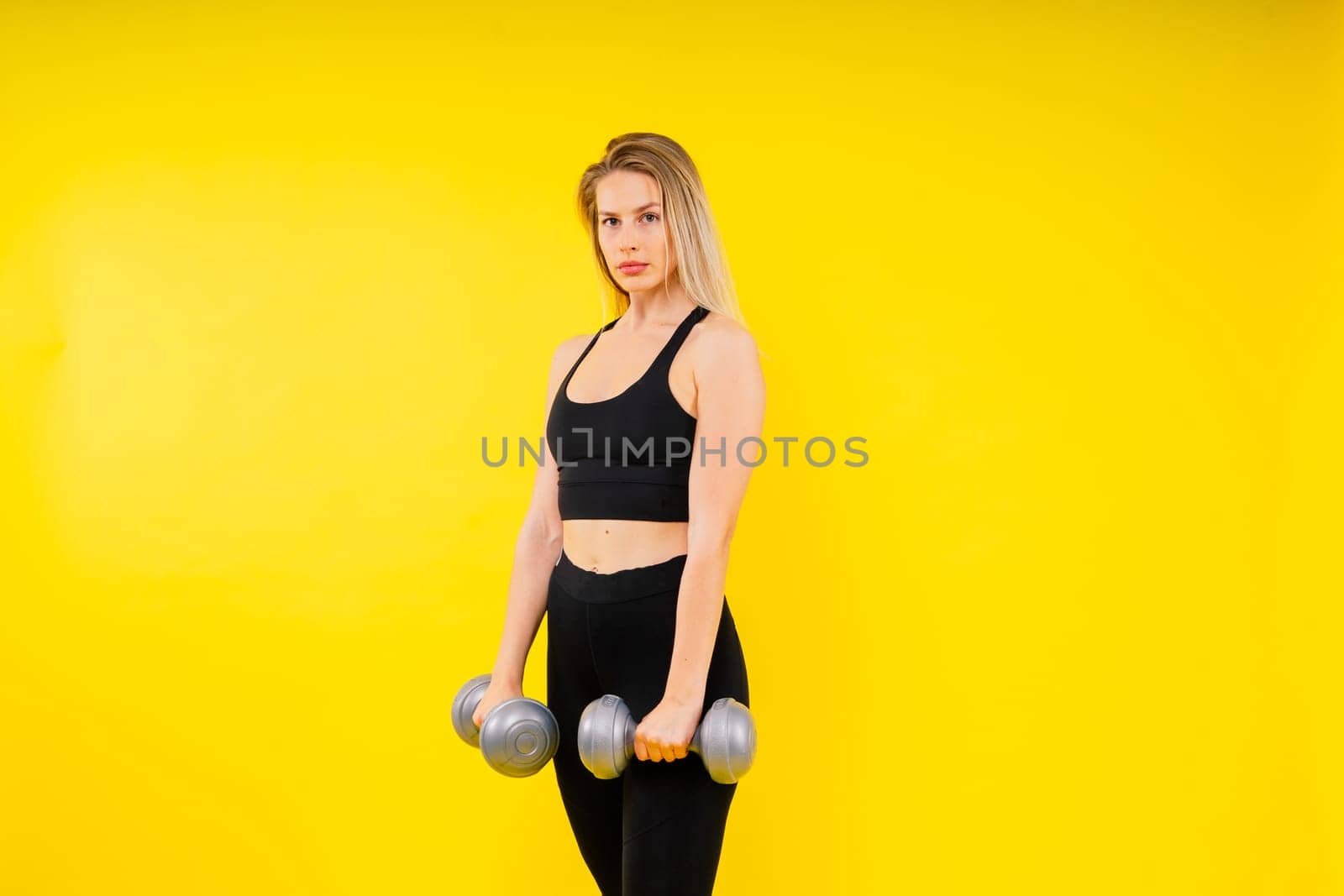 Perfect sporty female working out with dumbbells. Photo of woman in sportswear, studio shot