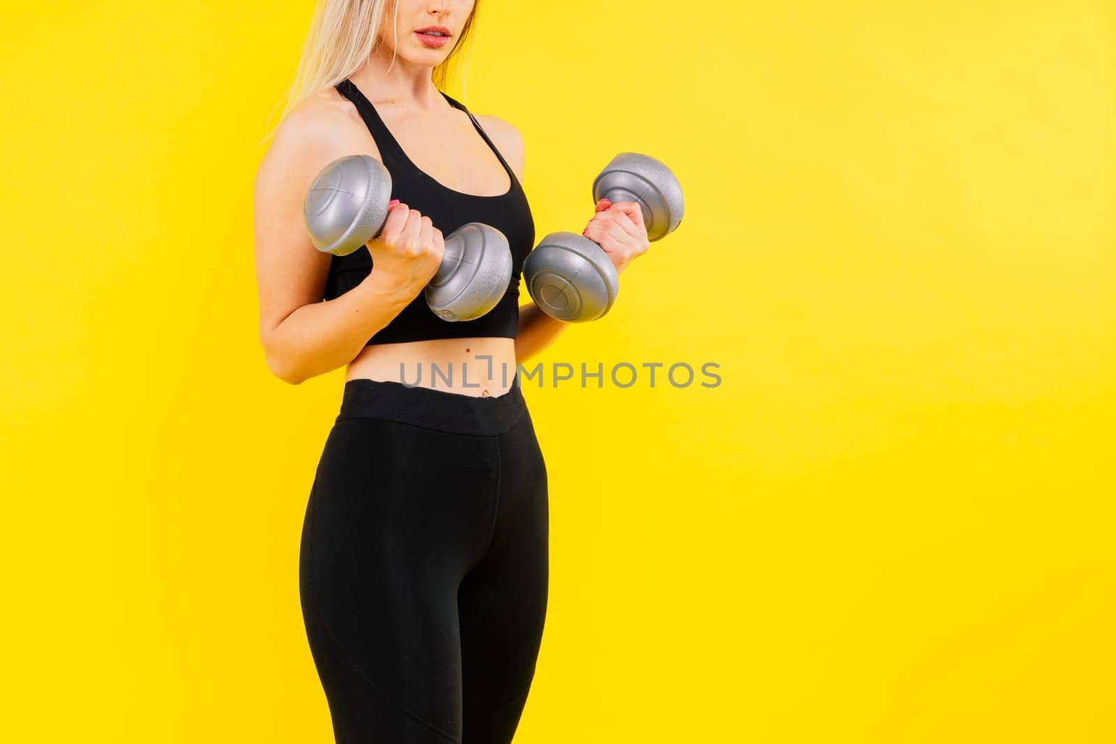 Perfect sporty female working out with dumbbells. Photo of woman in sportswear, studio shot
