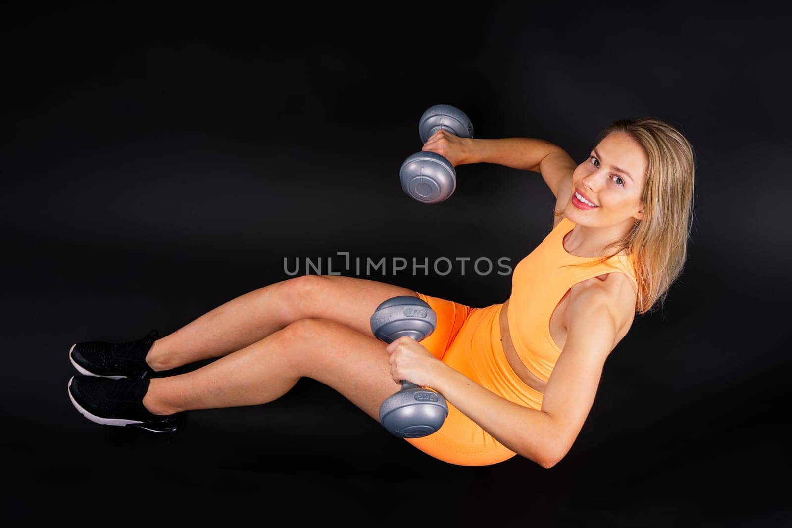 Perfect sporty female working out with dumbbells. Photo of woman in sportswear, studio shot