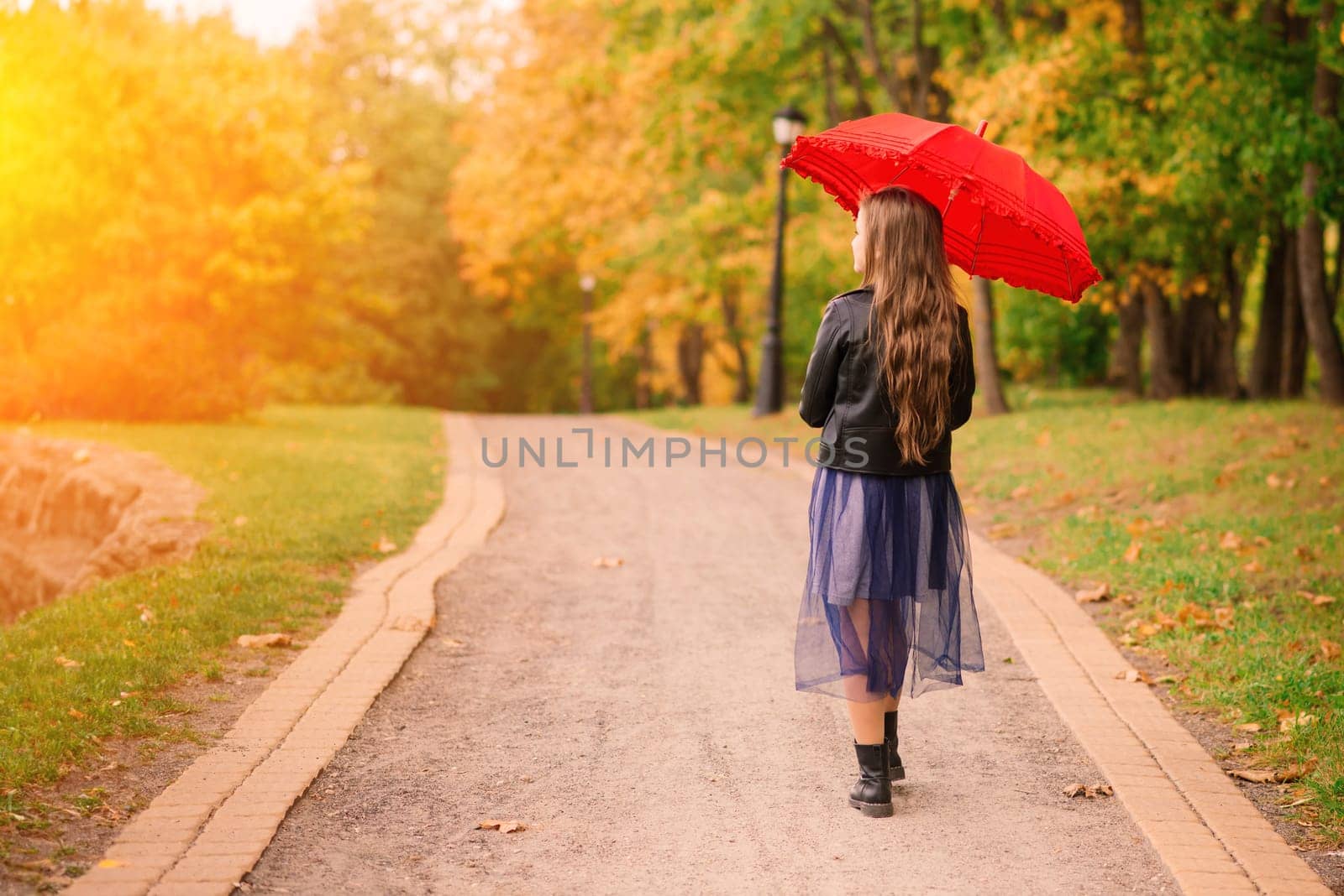 Young attractive smiling girl under umbrella in an autumn forest