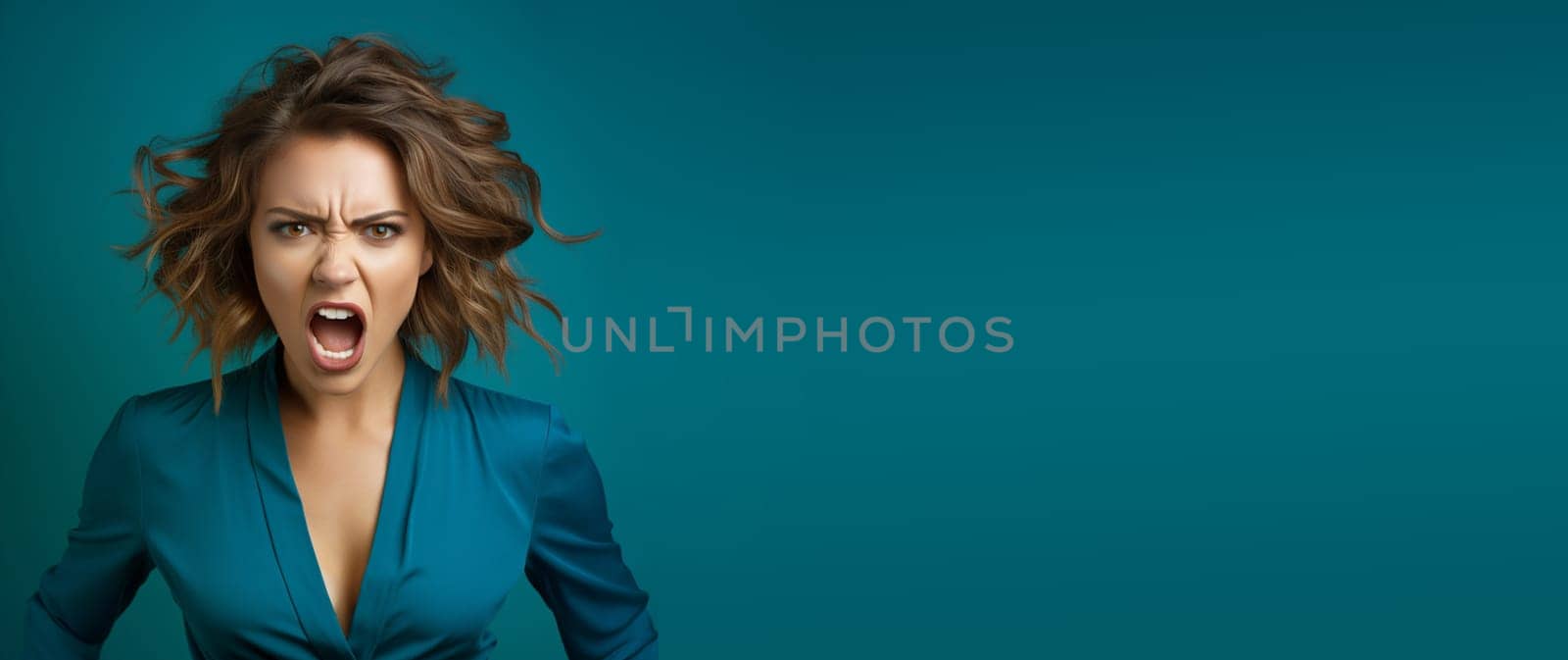 Portrait of an angry and frustrated young woman, screaming, aggressive face, negative emotion, blue background