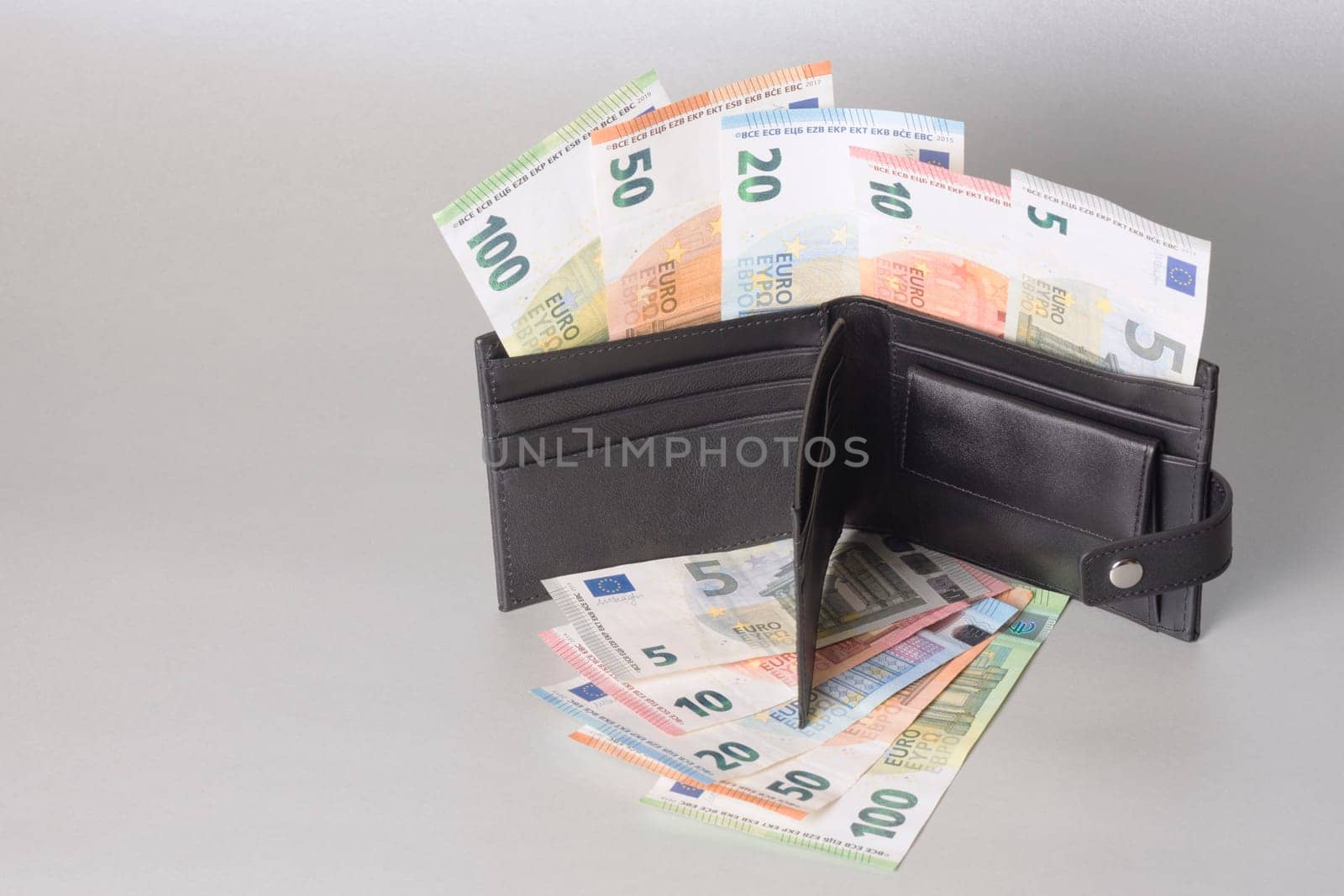Euro banknotes paper money, cash in black purse on gray background.