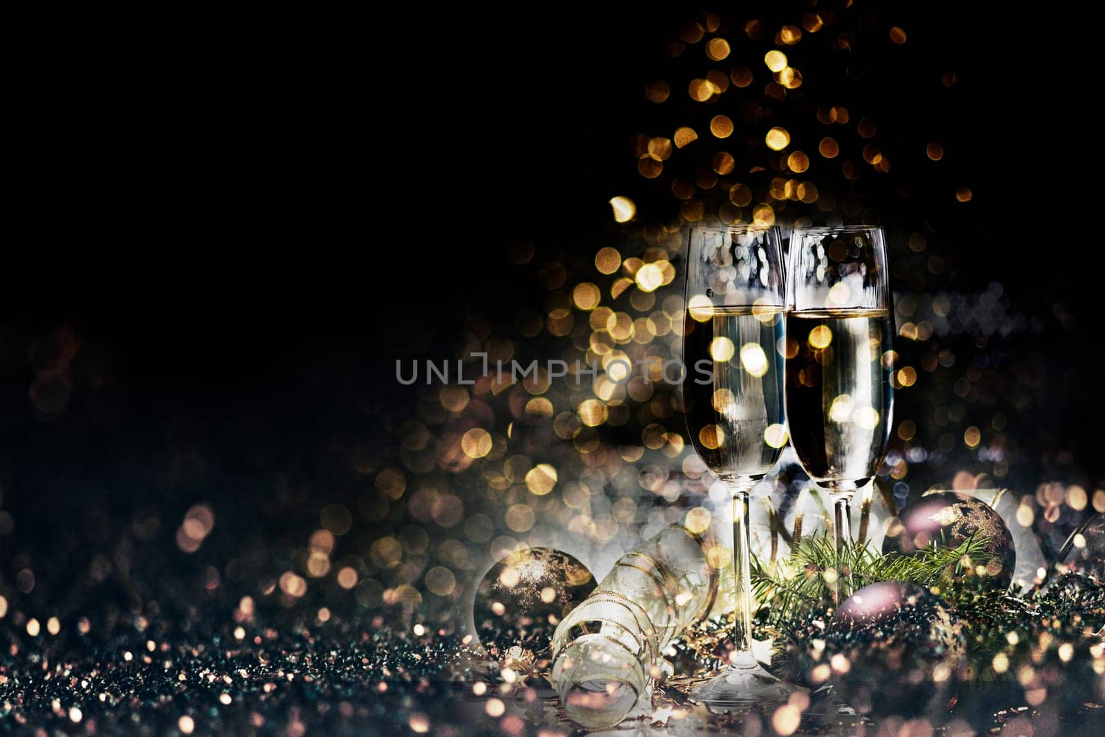 Two champagne glasses and christmas decoration over dark golden bokeh background. New year and christmas luxury party celebration. Sparkling new year 2020 backdrop layout design.