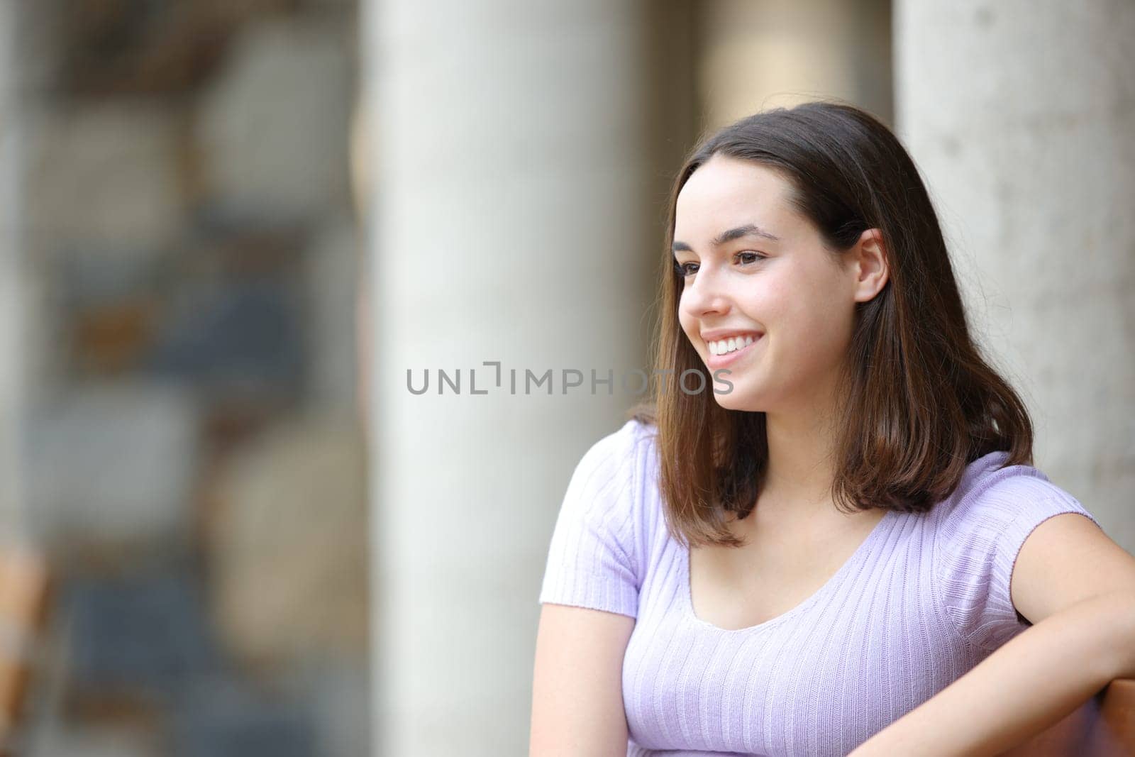 Happy woman sitting in the street looks away
