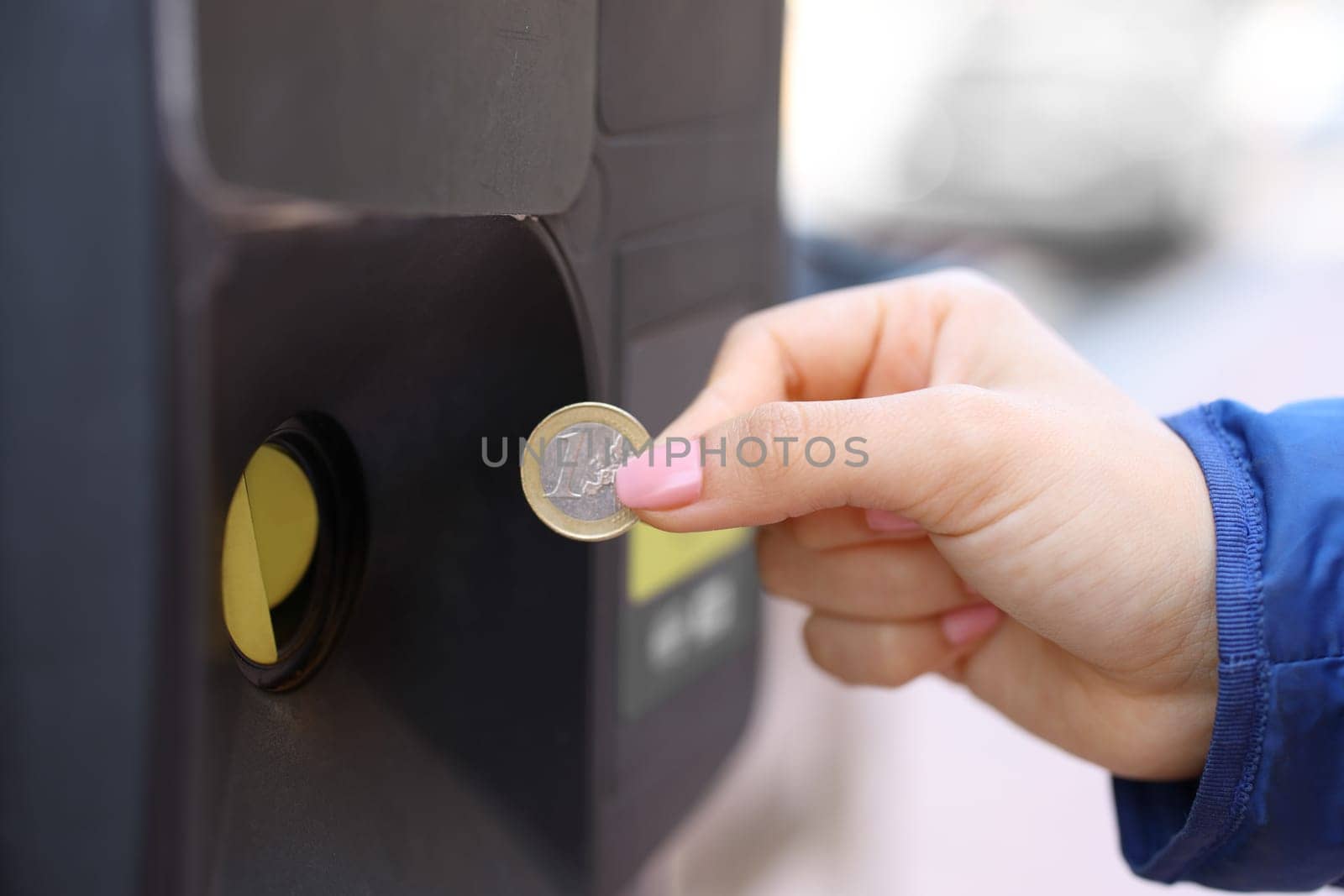 Close up portrait of a woman hand using coin to pay parking meter
