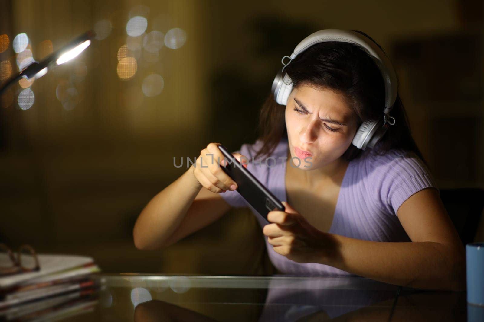 Woman playing online game with phone in the night at home
