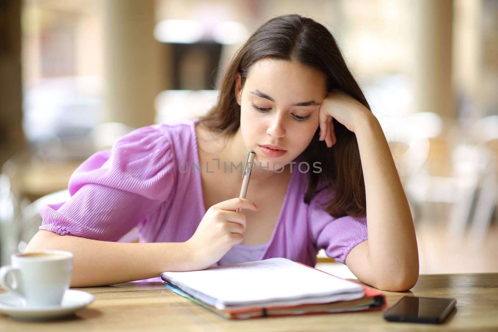Student memorizing notes sitting in a restaurant terrace