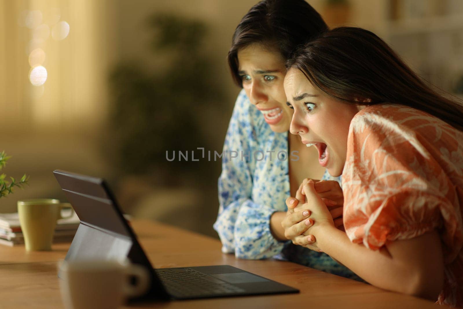 Terrified women watching media on laptop in the night at home
