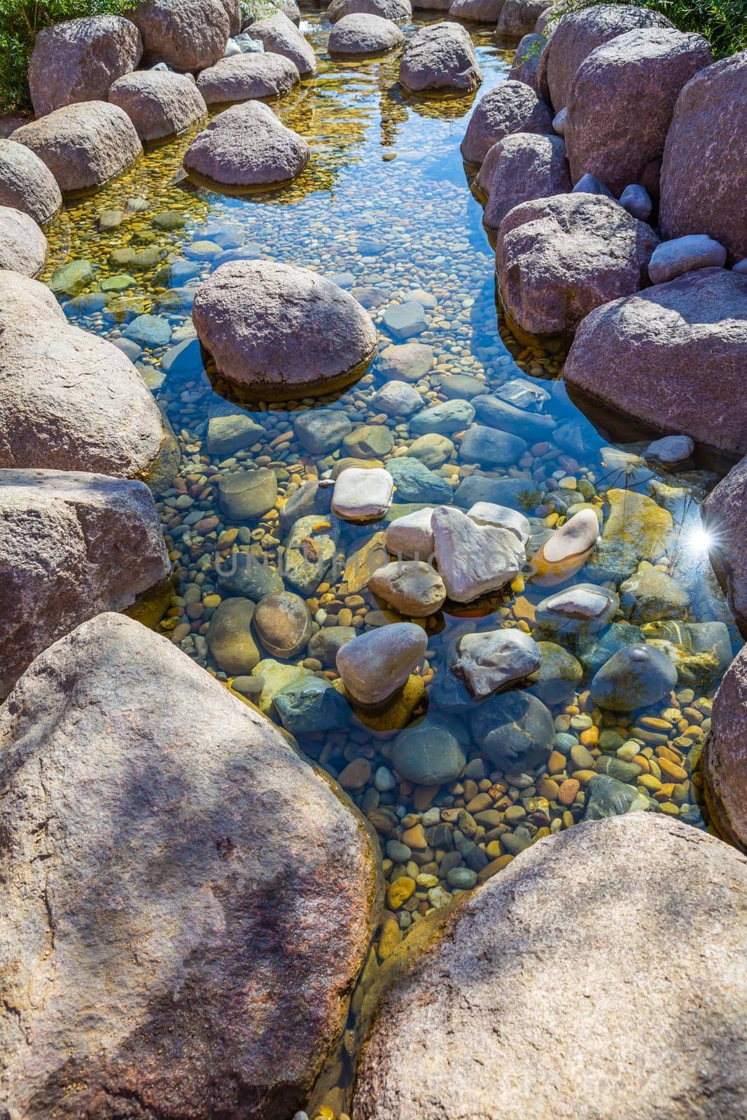 Small pond in a garden as landscaping design element with rock, pebbles and gravel