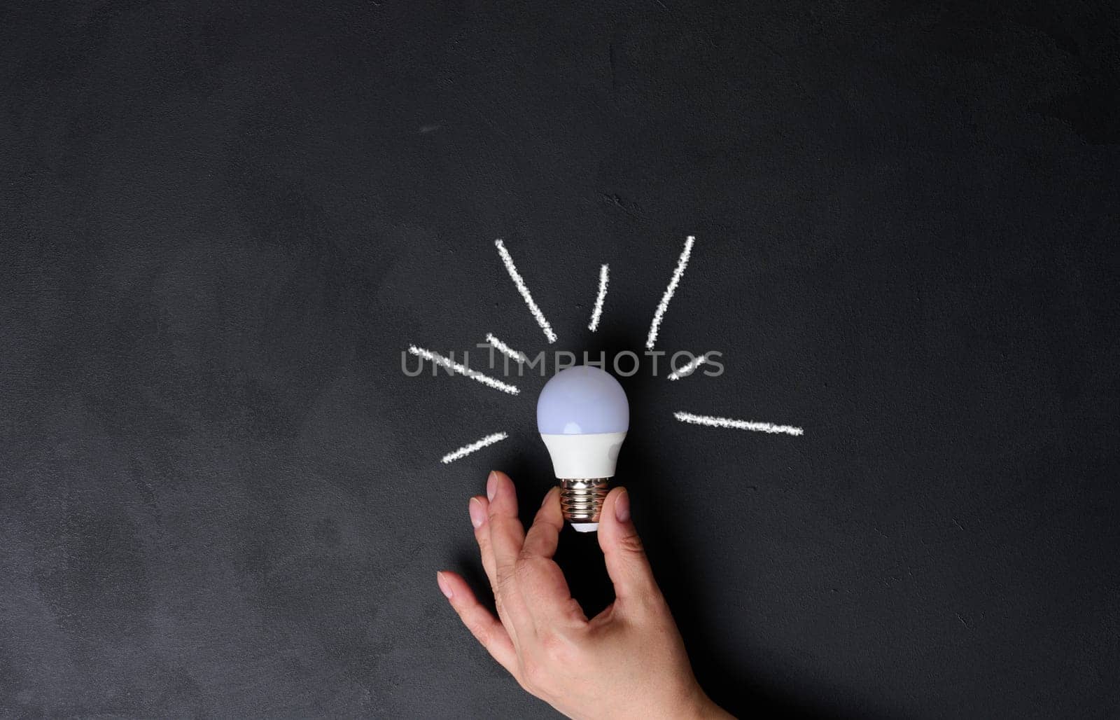 A woman's hand holds an electric lamp, the concept of searching for new ideas, startup