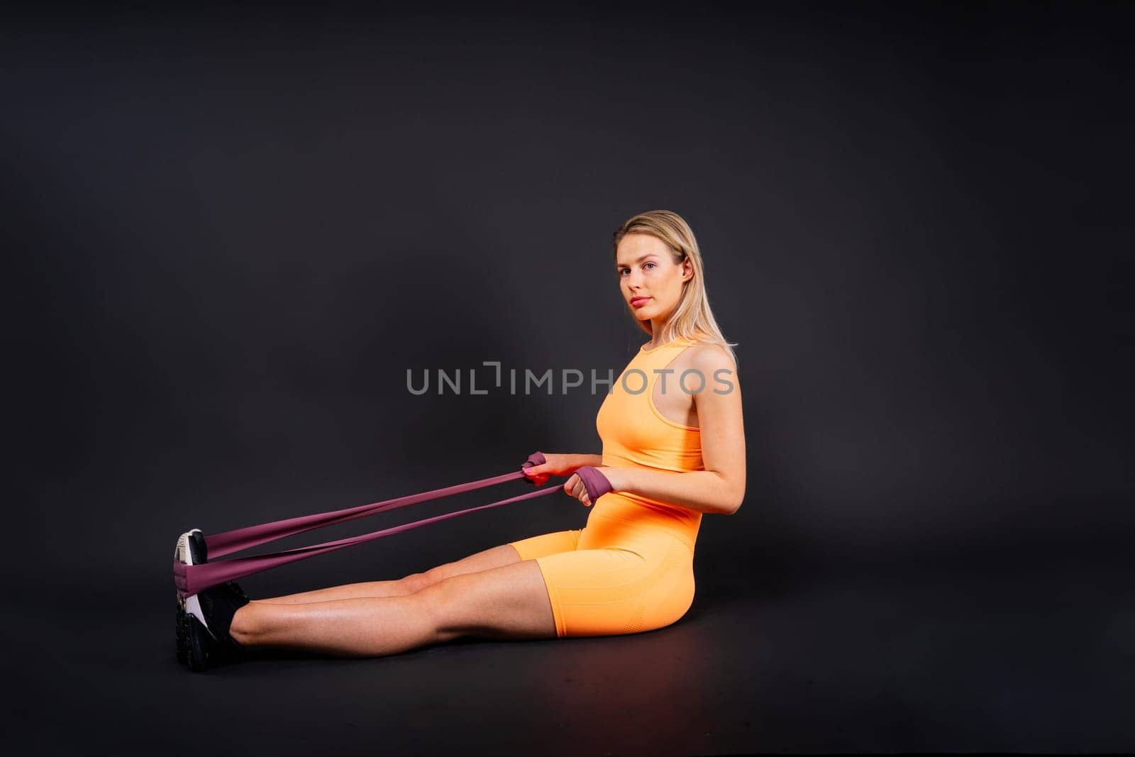 Fitness woman doing jumping exercises with a skipping rope on colorful yellow background.