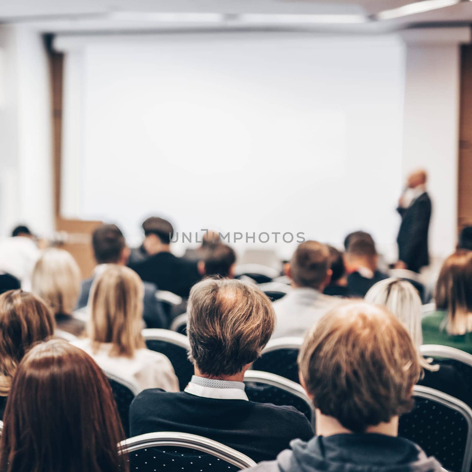 Speaker giving a talk in conference hall at business event. Rear view of unrecognizable people in audience at the conference hall. Business and entrepreneurship concept